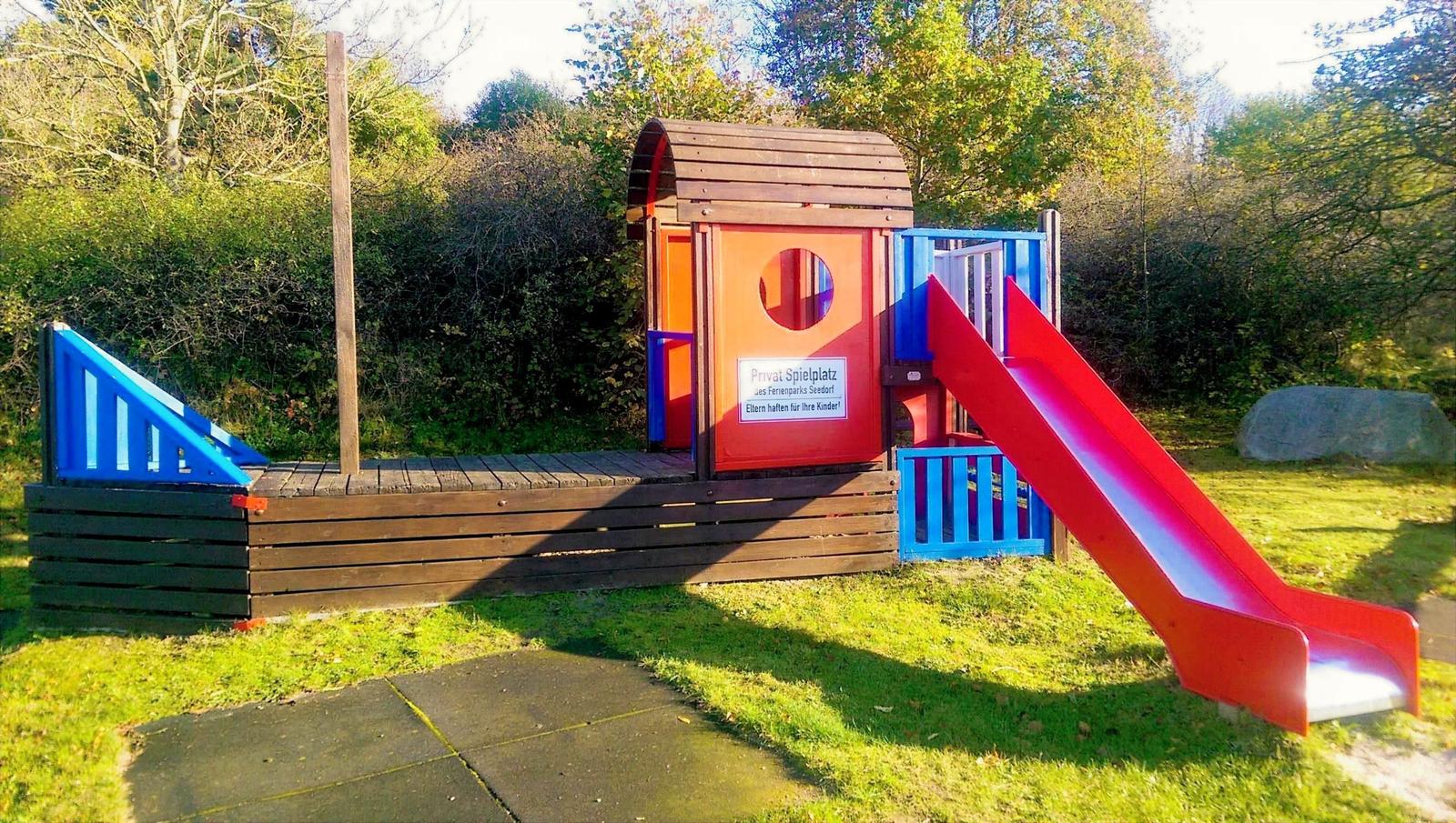 Farbiger Spielplatz mit Rutsche und Klettergerüst im Garten.