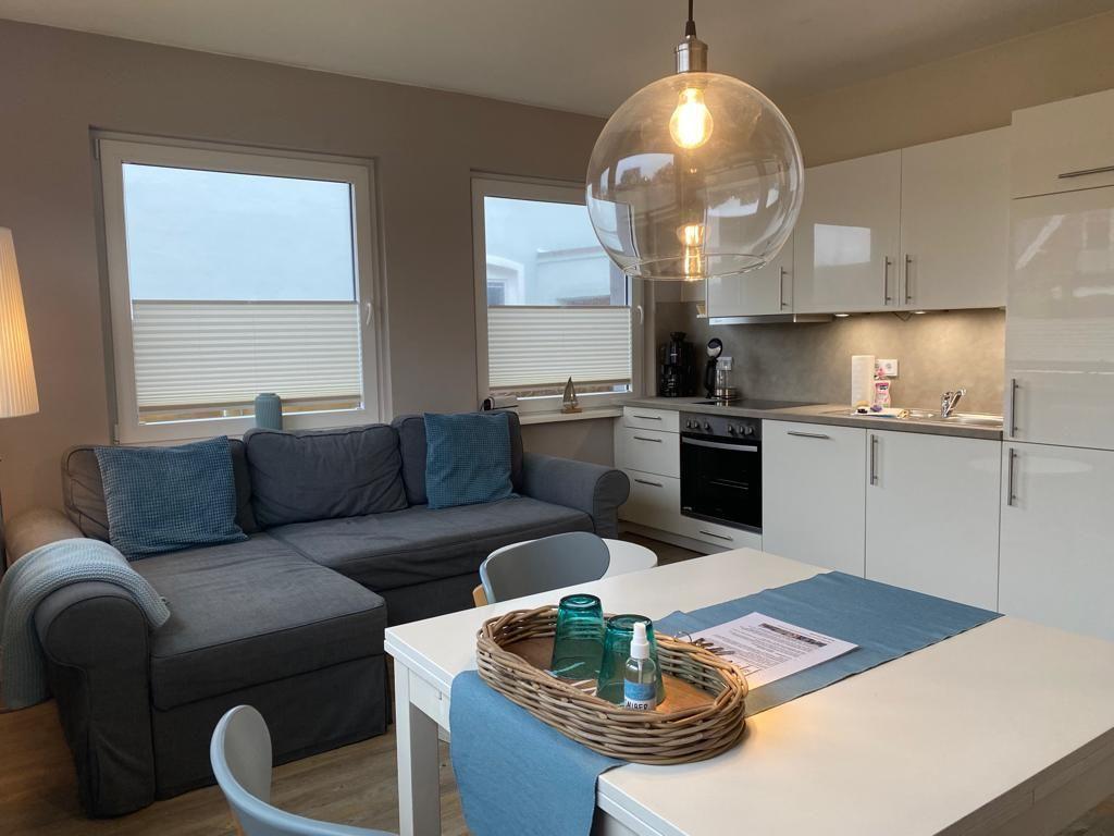 Wohn- und Küchenbereich mit Sofa, Esstisch und moderner Beleuchtung.