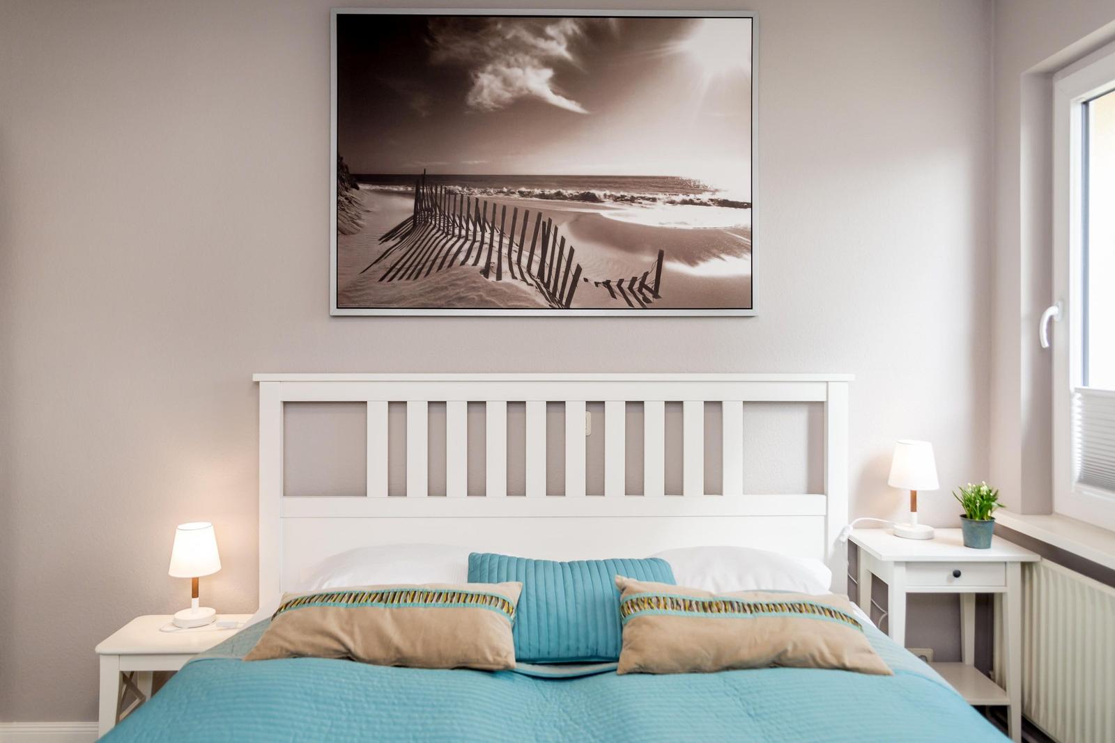 Schlafzimmer mit weißem Bett und Wandbild an der Wand