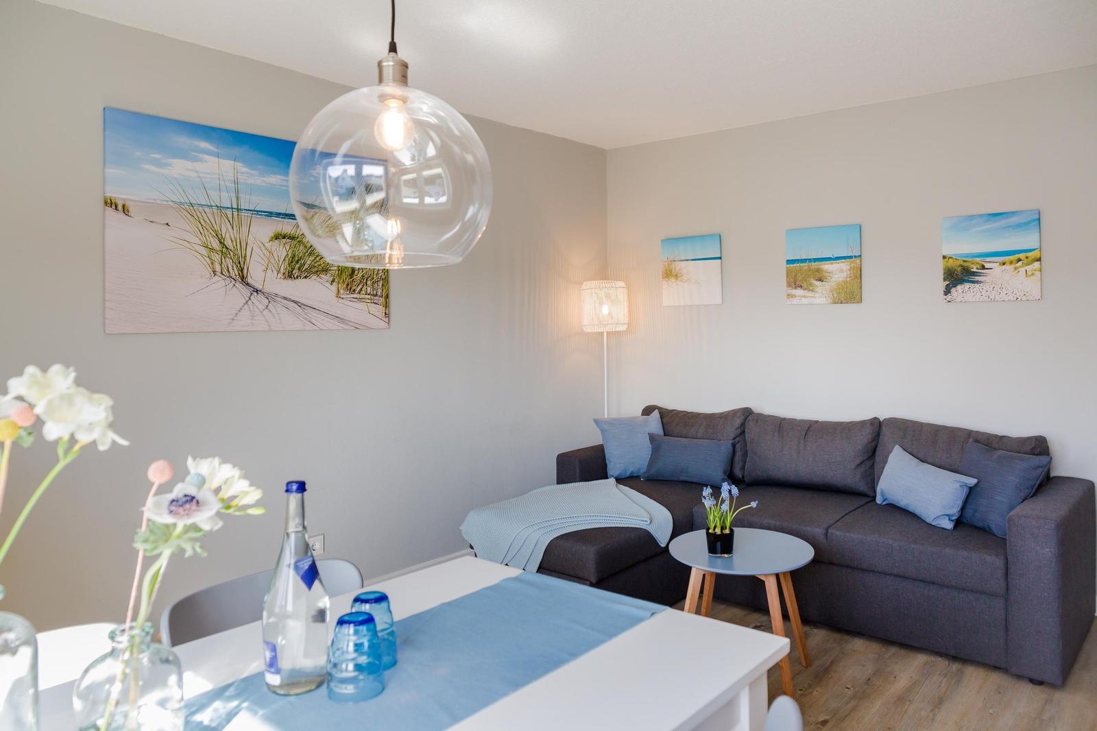 Wohnzimmer mit Sofa, Tisch und Wandbildern von Strand