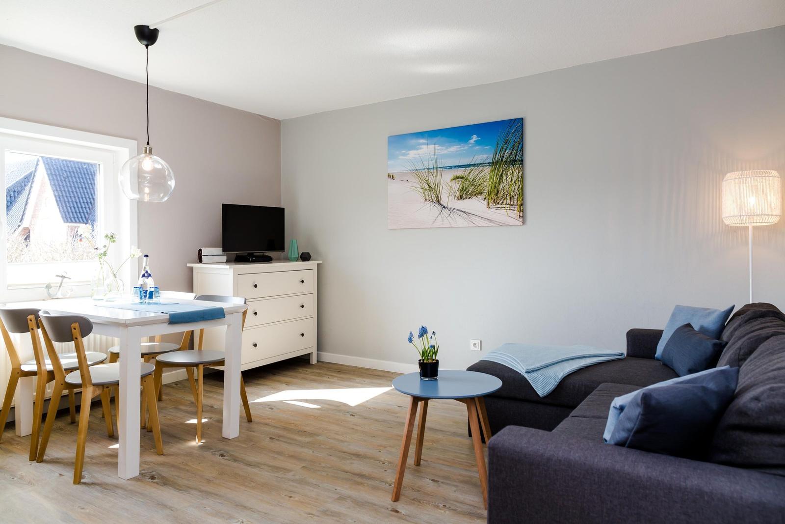 Wohn- und Essbereich mit Sofa, Tisch und Wandbild.