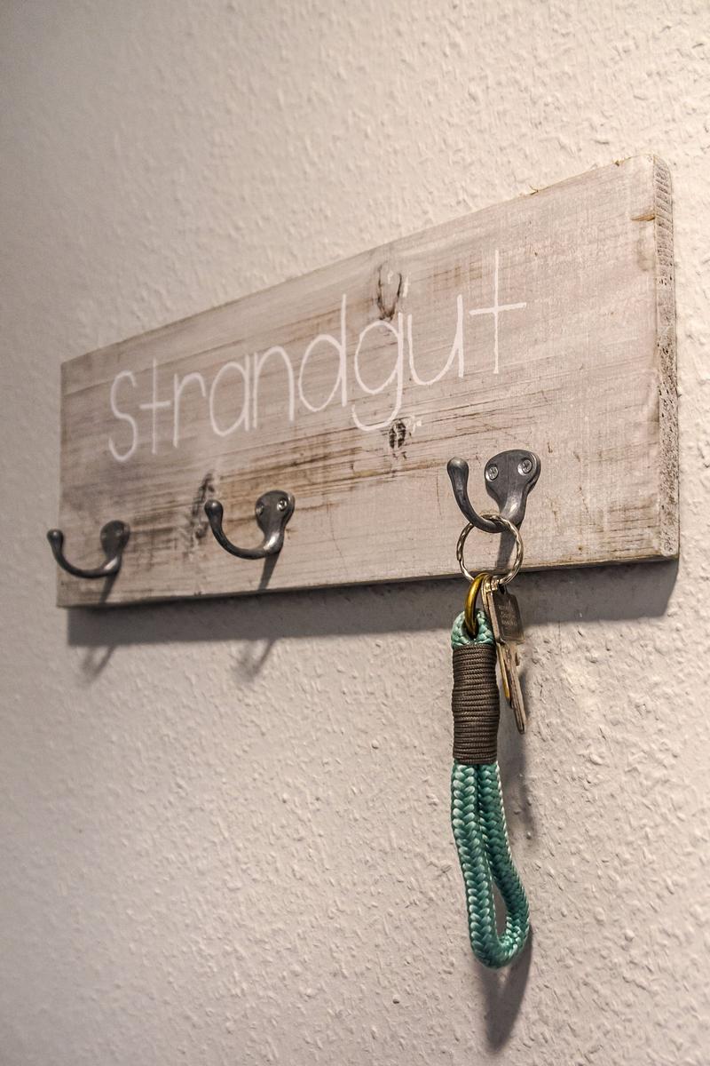 Holz-Haken mit Schriftzug Strandgut und Schlüsselanhänger an Wand