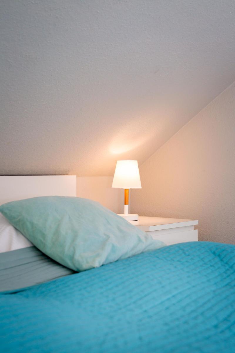 Bedroom with bed, nightstand, and lamp under sloped ceiling.