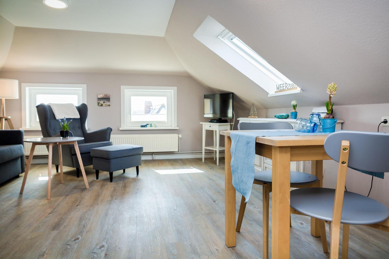 Attic apartment with dining area, seating, and skylight.