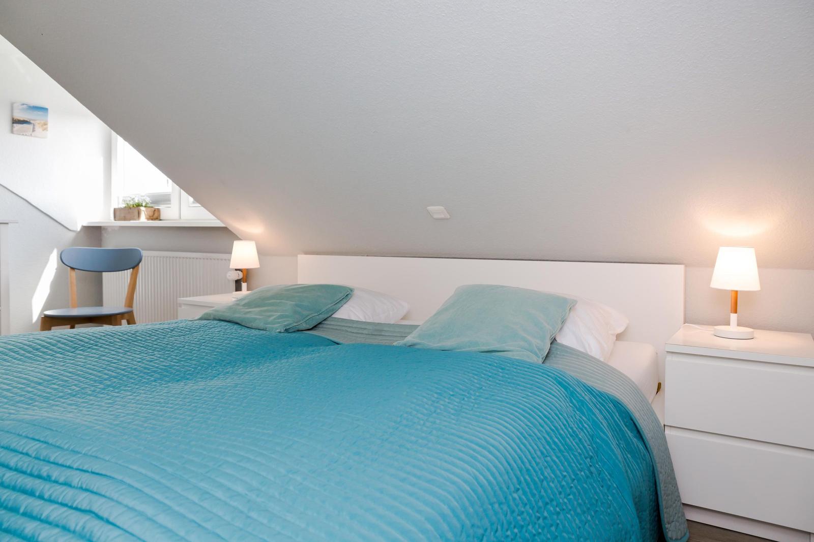Bedroom with bed, nightstands, and lamp under sloped ceiling