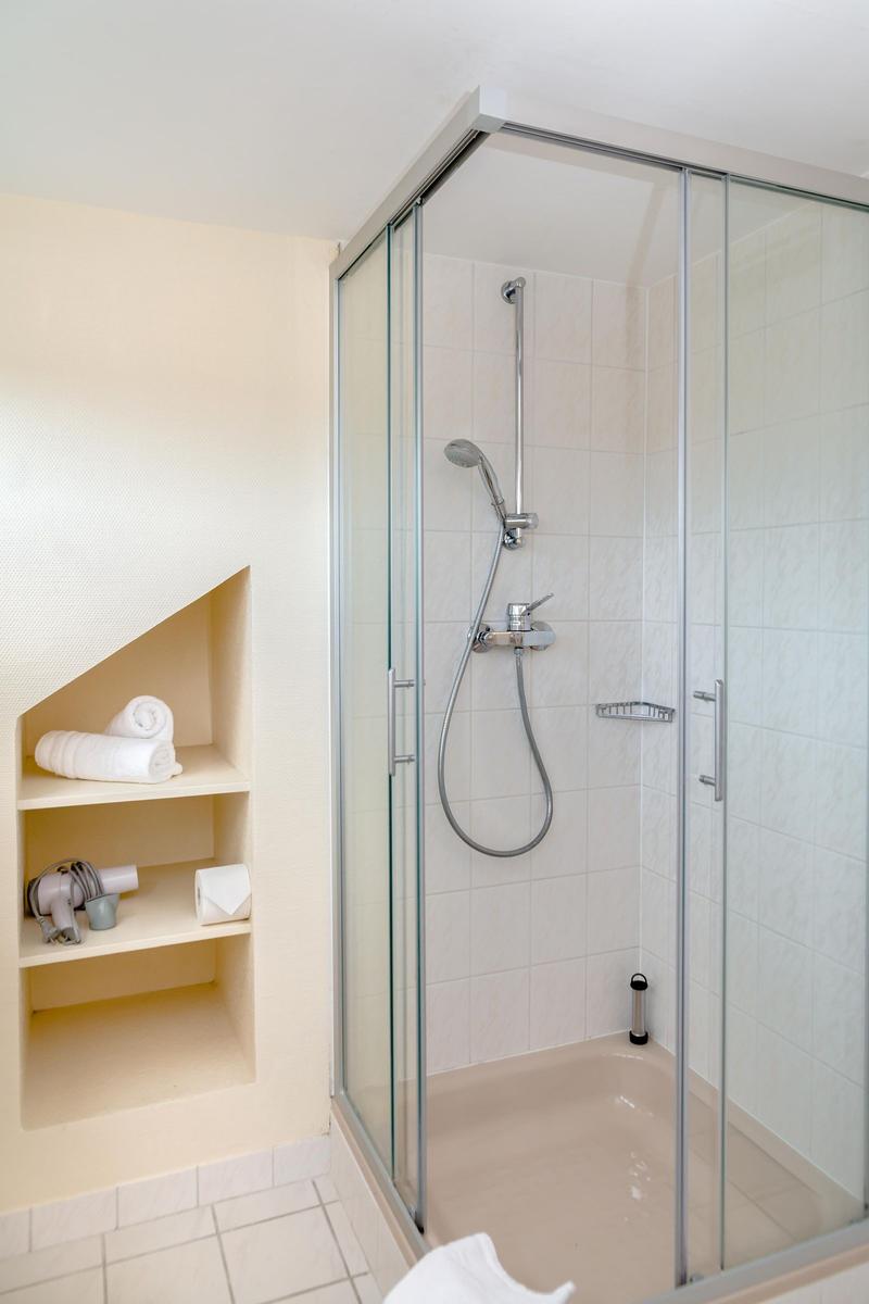 Shower with glass enclosure and built-in shelf for towels and toiletries.