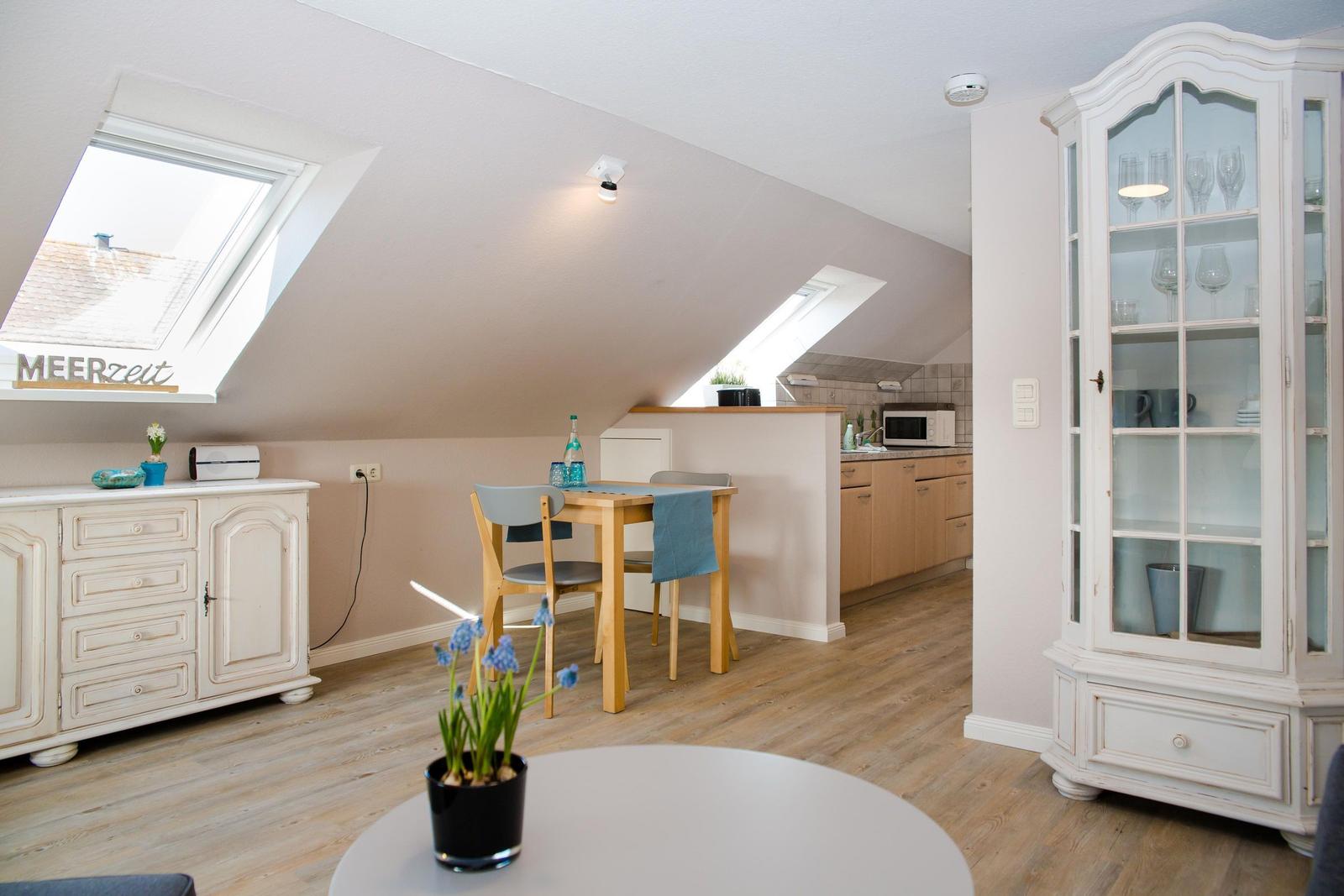 Attic apartment with dining area, kitchen, and cabinet. Skylights and wooden floor.