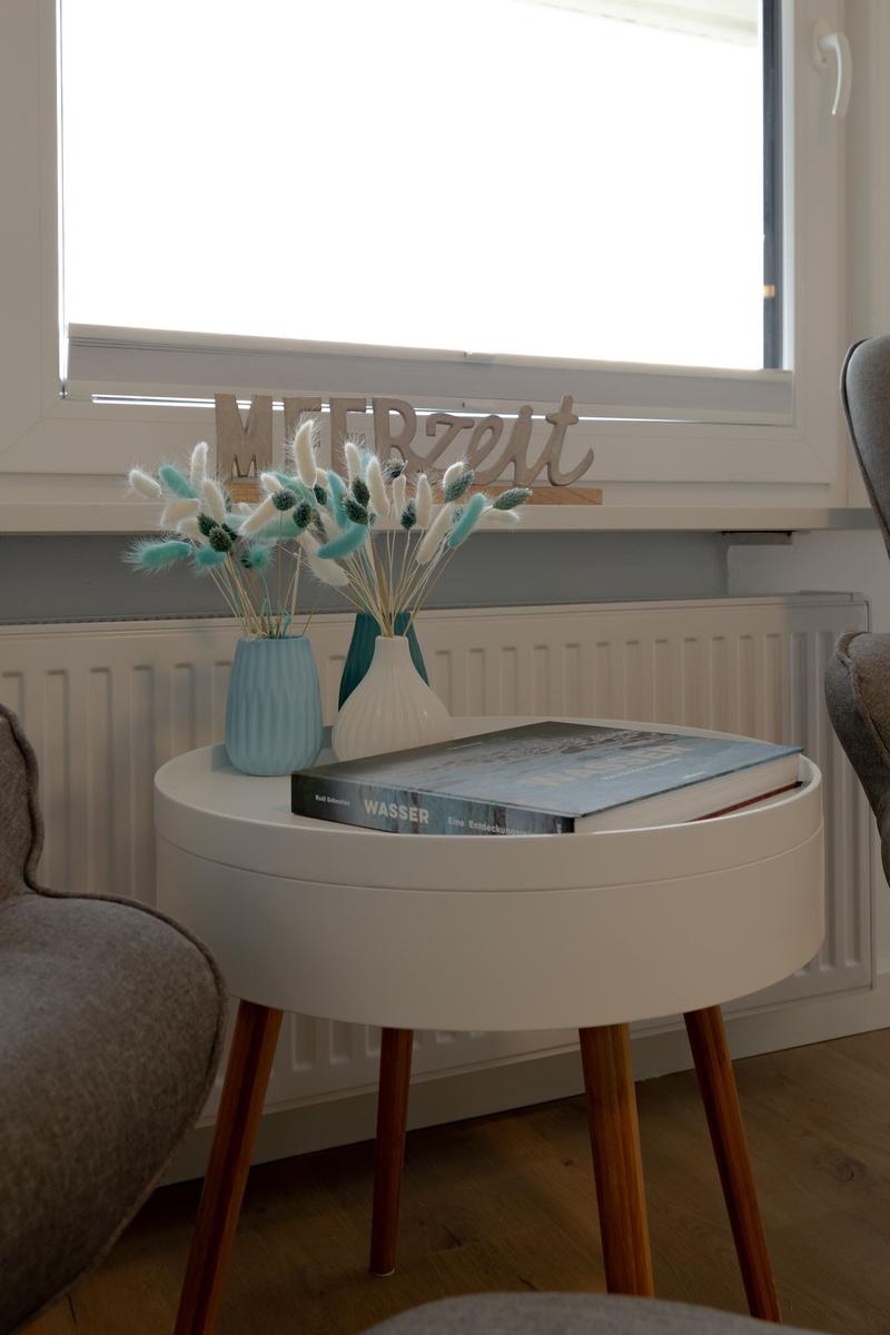 Runder Tisch mit Büchern und Vasen vor Fenster