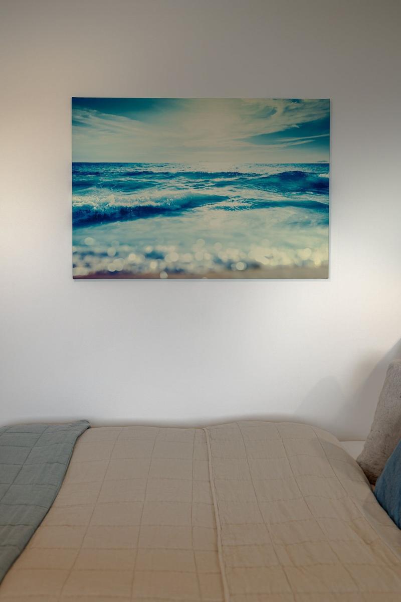 Ein Bett mit Bettwäsche und Wandbild mit Meeresmotiv.