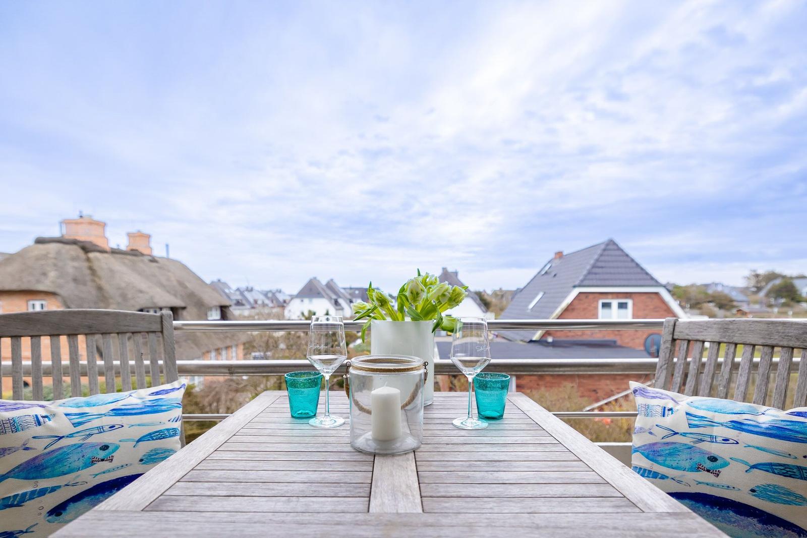 Terrasse mit Tisch, Stühlen und Blick auf Dächer.