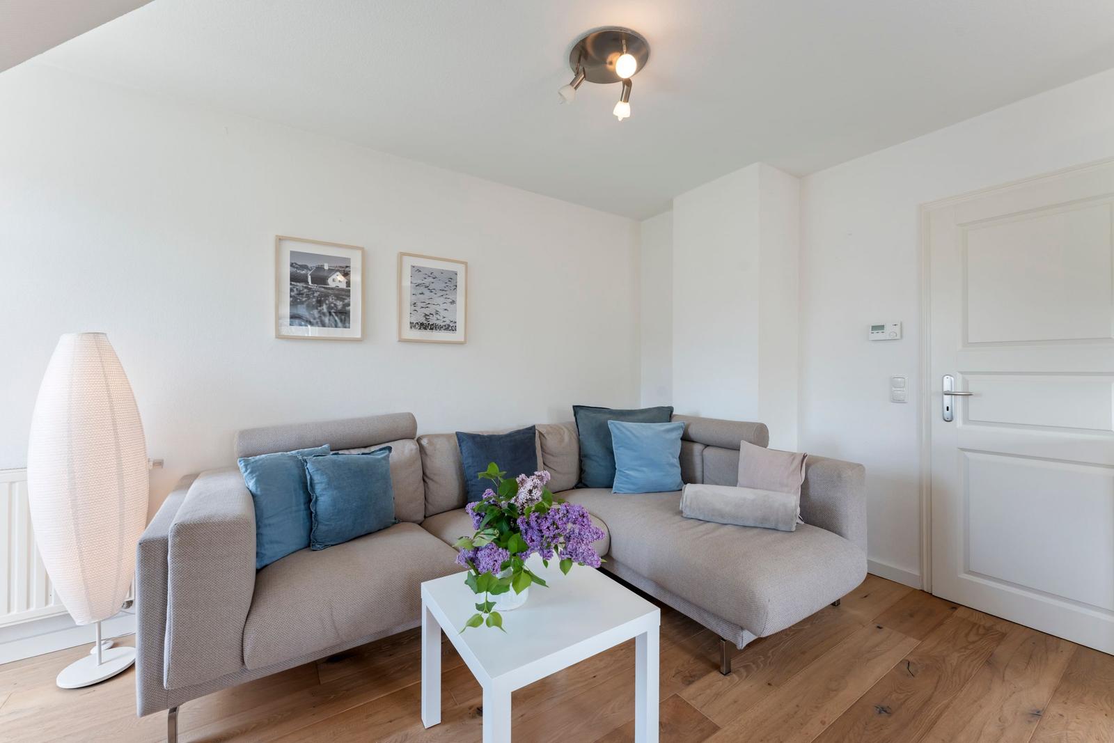Ein Wohnzimmer mit einem grauen Sofa, blauen Kissen und einem weißen Couchtisch.