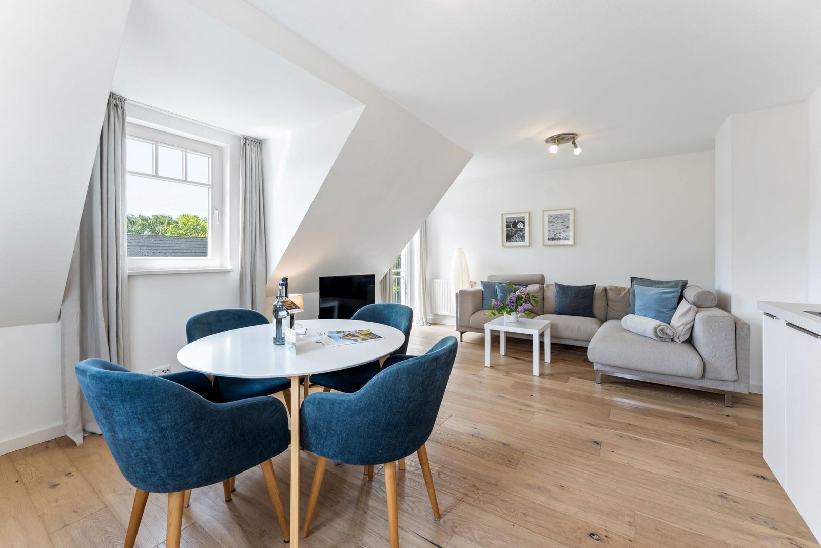 Wohnbereich mit Essplatz, Sofa und Holzboden unter schrägen Dachdecken.