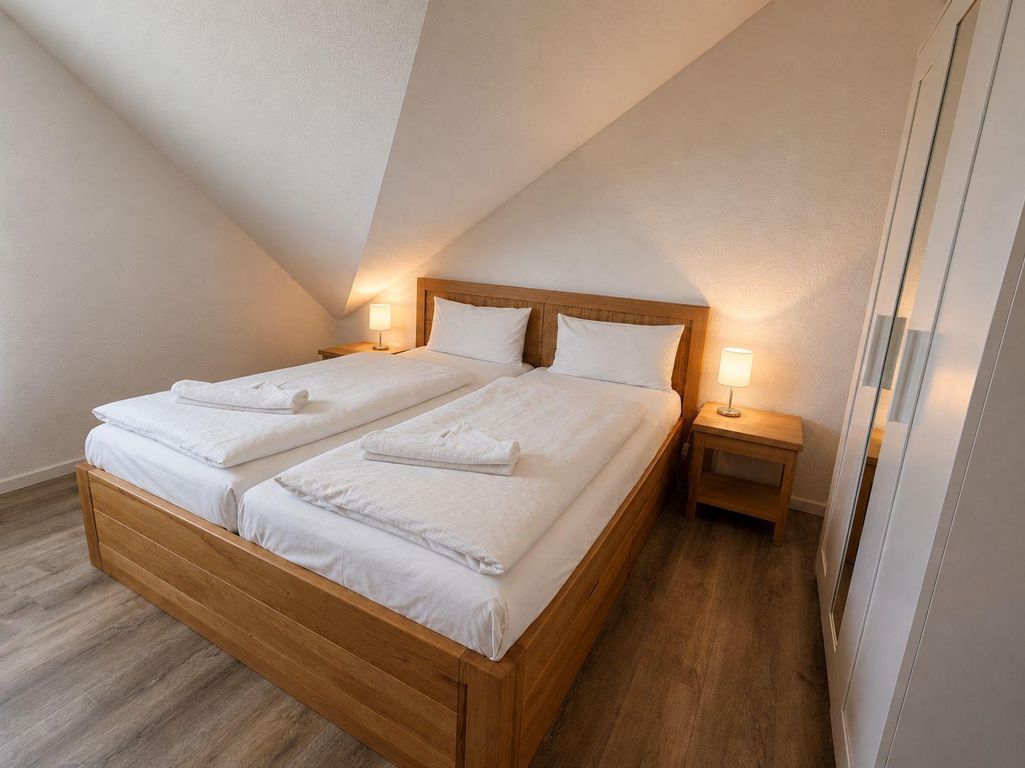 Schlafzimmer mit Doppelbett, zwei Nachttischen und einer Kleiderschrankwand.