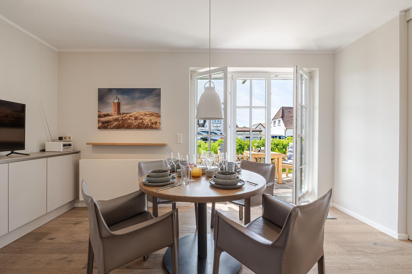 Esszimmer mit runder Tisch und Stühlen, Blick auf Balkon und Garten.