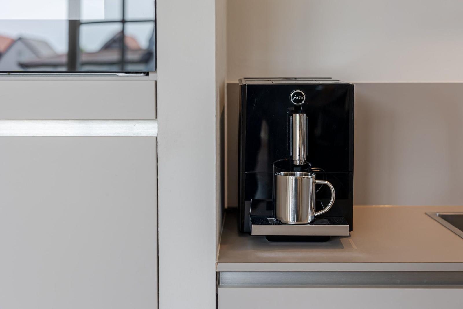 Eine schwarze Kaffeemaschine mit Edelstahlbecher auf einer Arbeitsfläche.