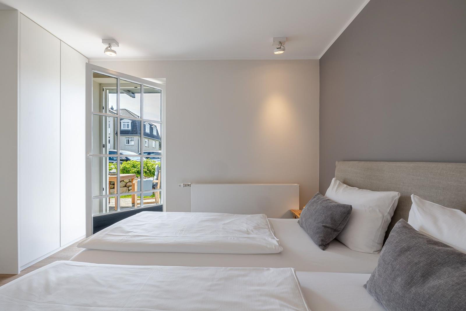 Schlafzimmer mit Bett, Fenster und Kleiderschrank. Blick auf Garten und Straße.