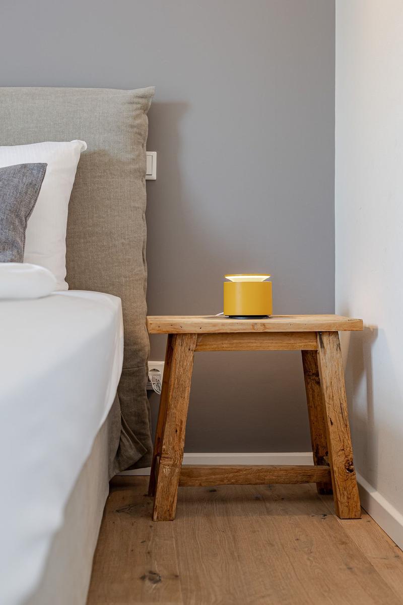Schlafzimmer mit Bett, Holztisch und gelber Lampe