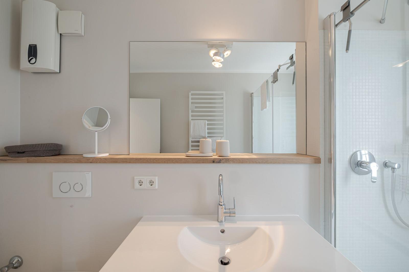 Badezimmer mit Waschbecken, Spiegel und Dusche