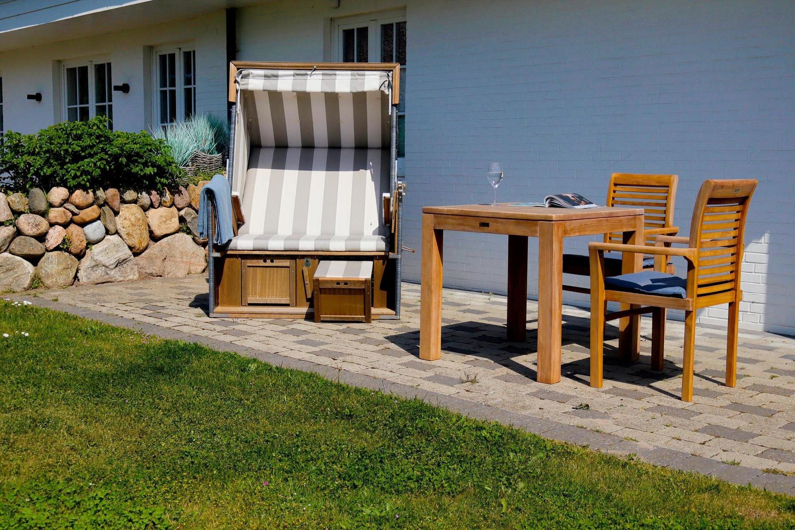 Terrasse mit Liegestuhl, Tisch und Stühlen vor einem Haus