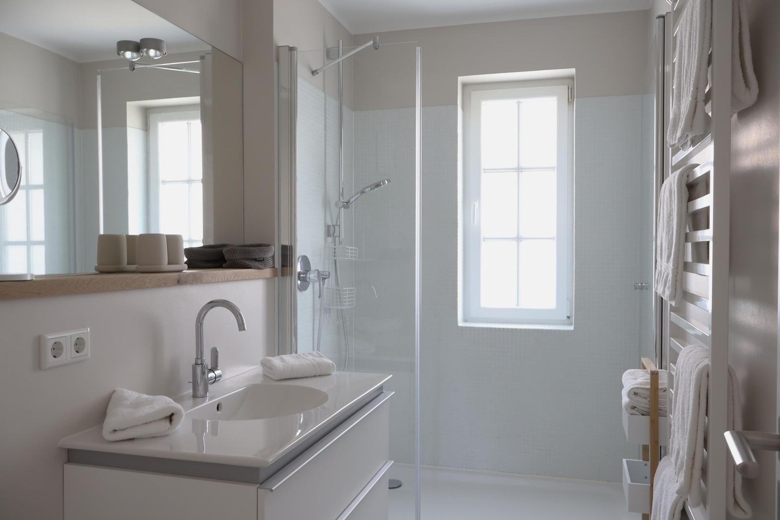 Badezimmer mit Dusche, Waschbecken und Fenster.