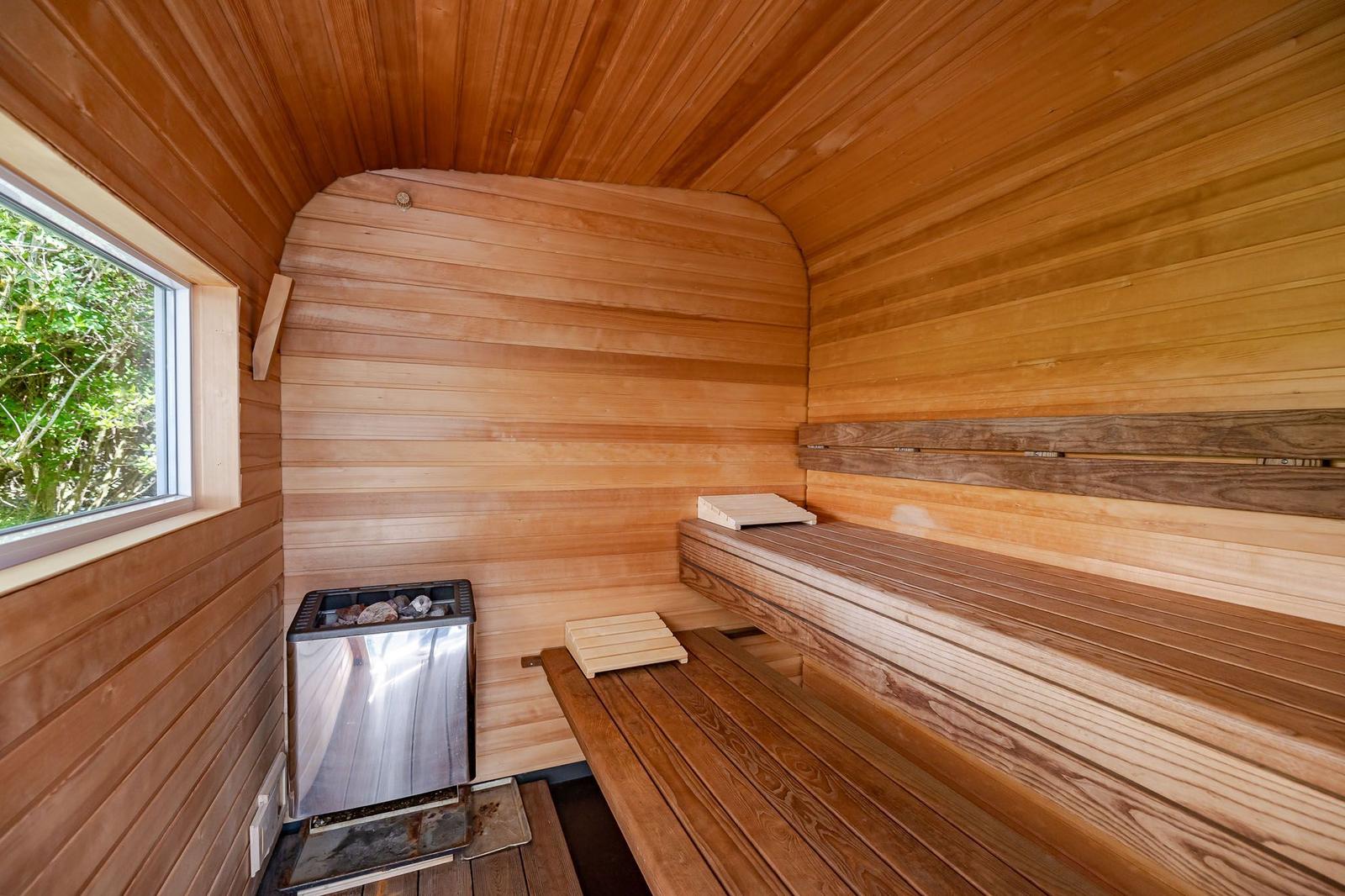 Sauna mit Holzbank, Heizung und Fenster zur grünen Außenwelt.