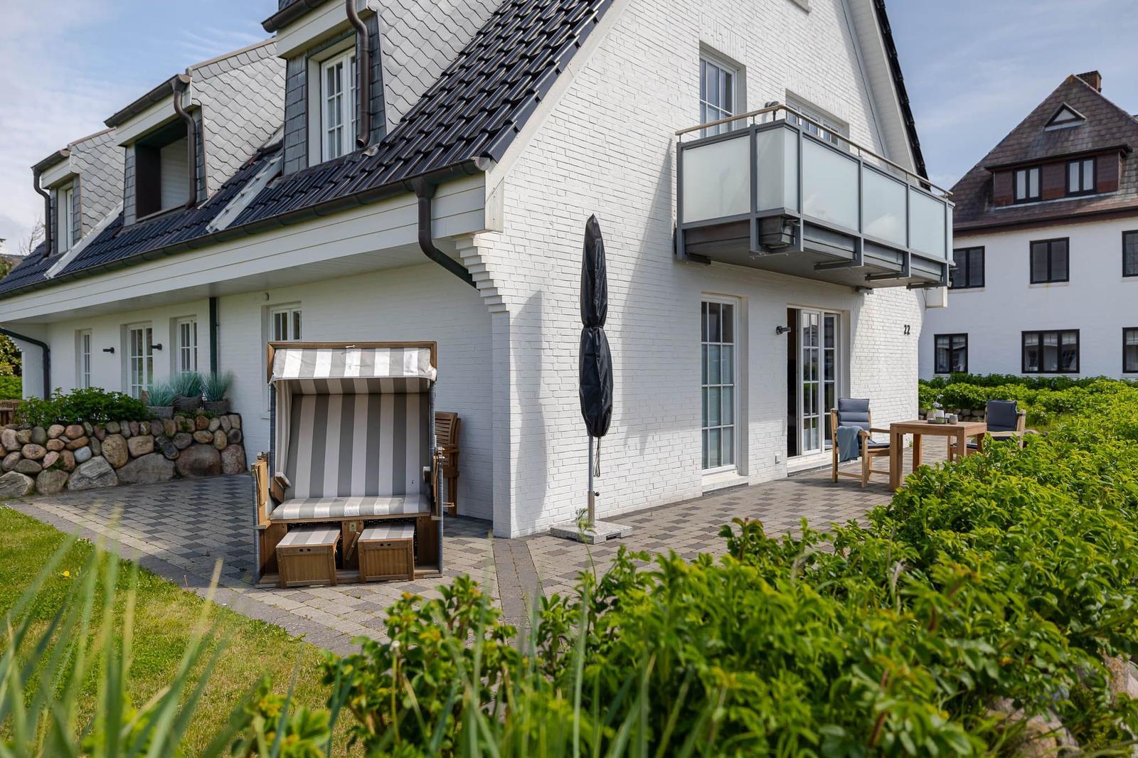 Wohnhaus mit Balkon, Strandkorb und Terrasse im Garten.