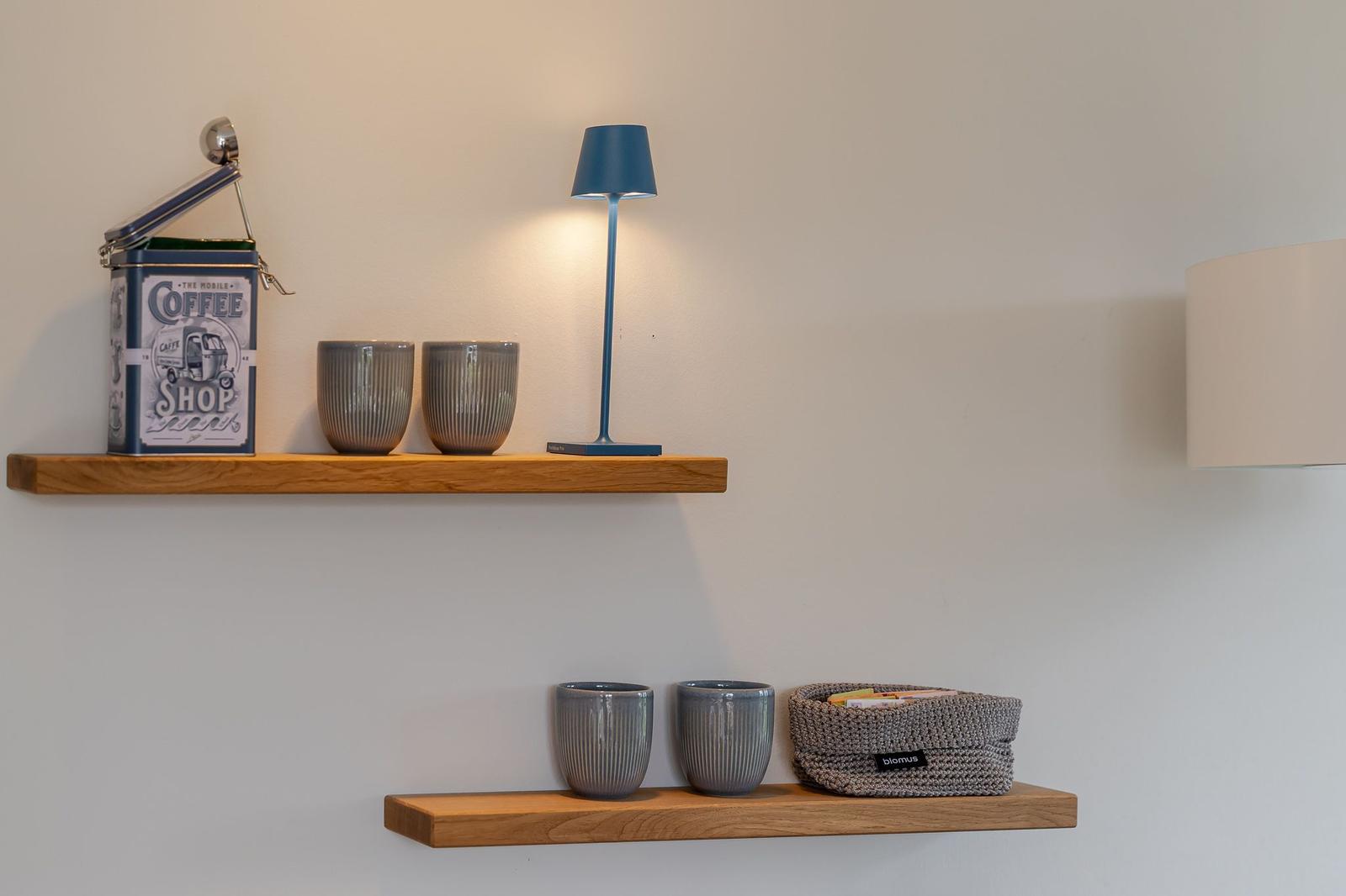 Zwei Holzregale mit Tassen, einer Lampe und einem Kaffeetöpfchen.