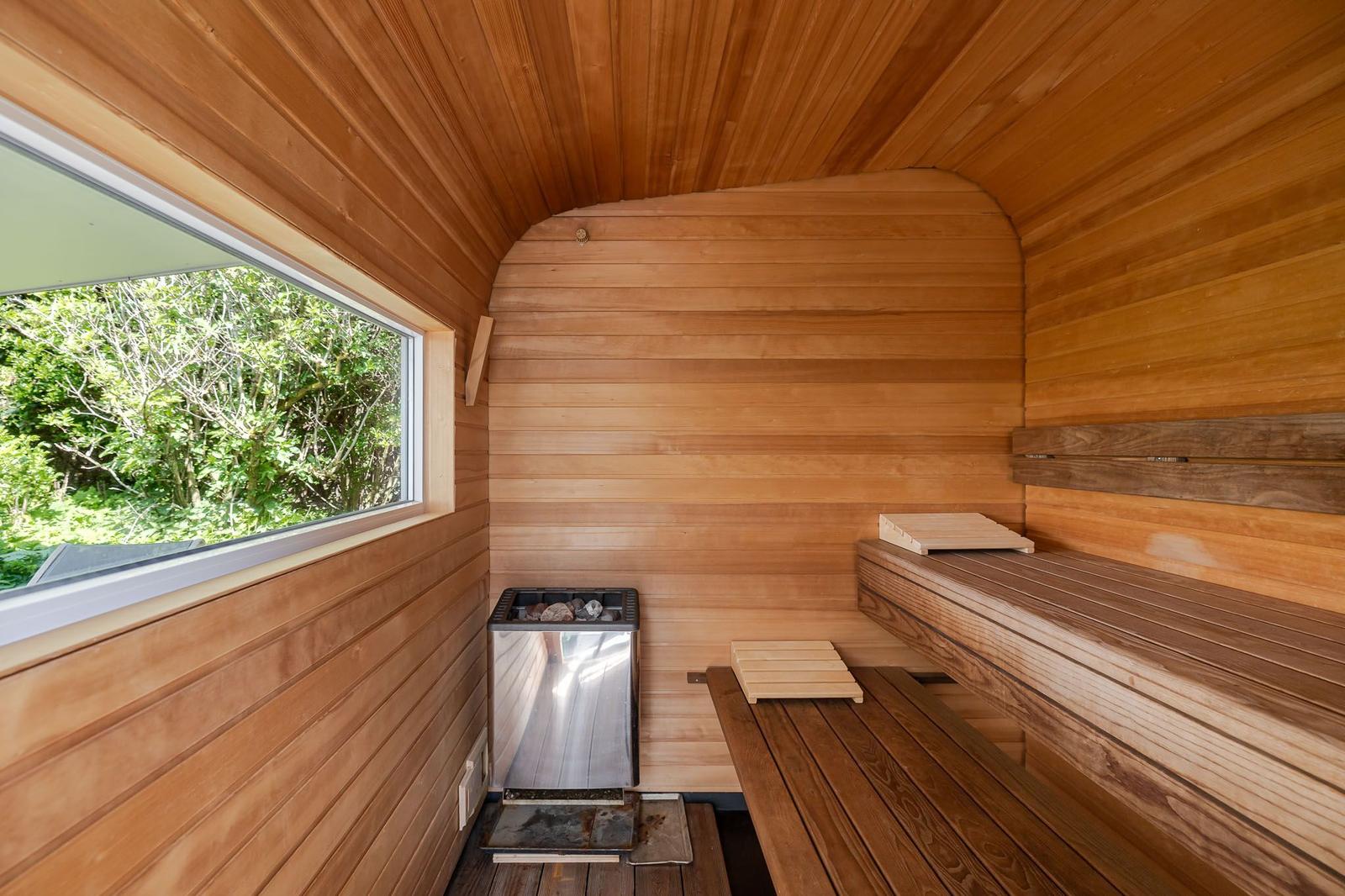 Sauna mit Holzwand, Sitzbänken und Fenster zum Garten.