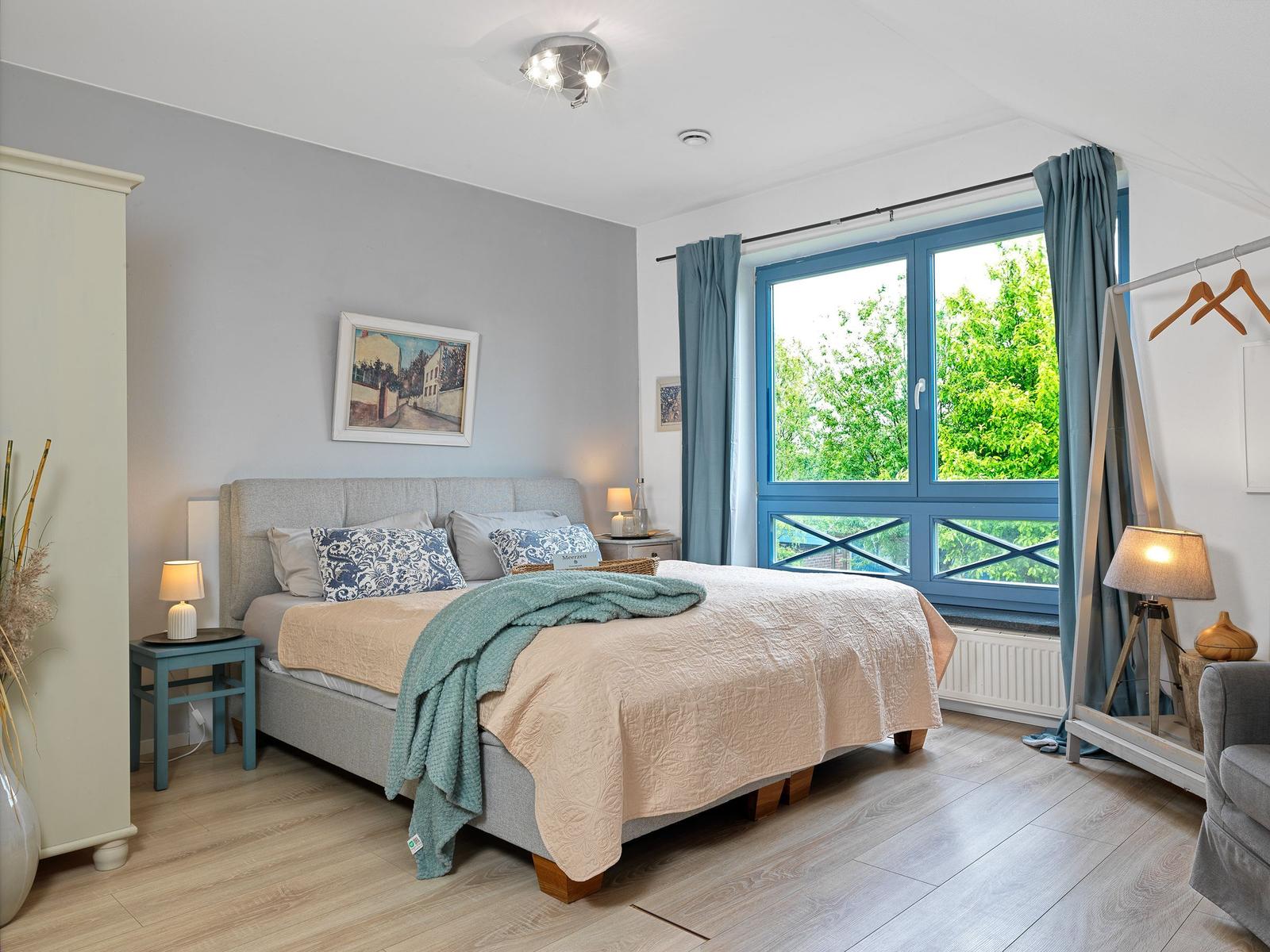 Schlafzimmer mit Bett, Fenster und Kleiderschrank.