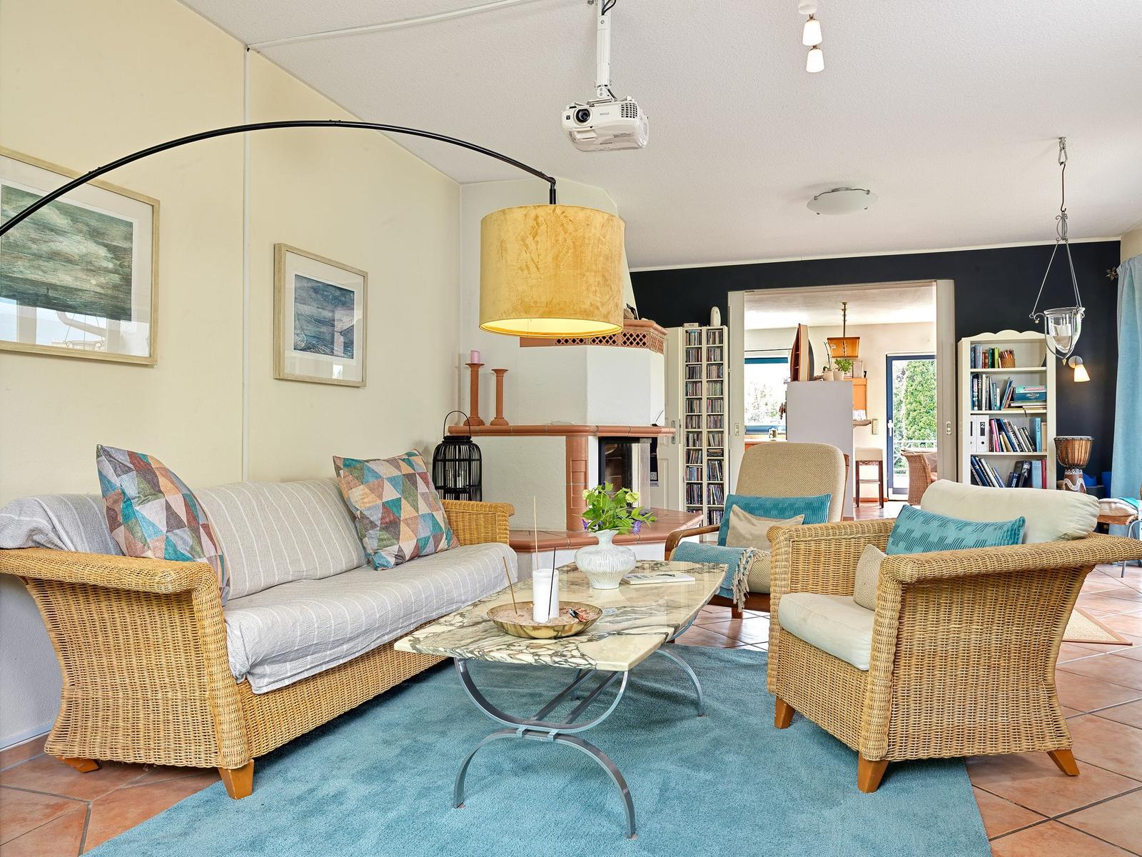 Wohnzimmer mit Rattan-Sofa, Sessel und Couchtisch auf Teppich