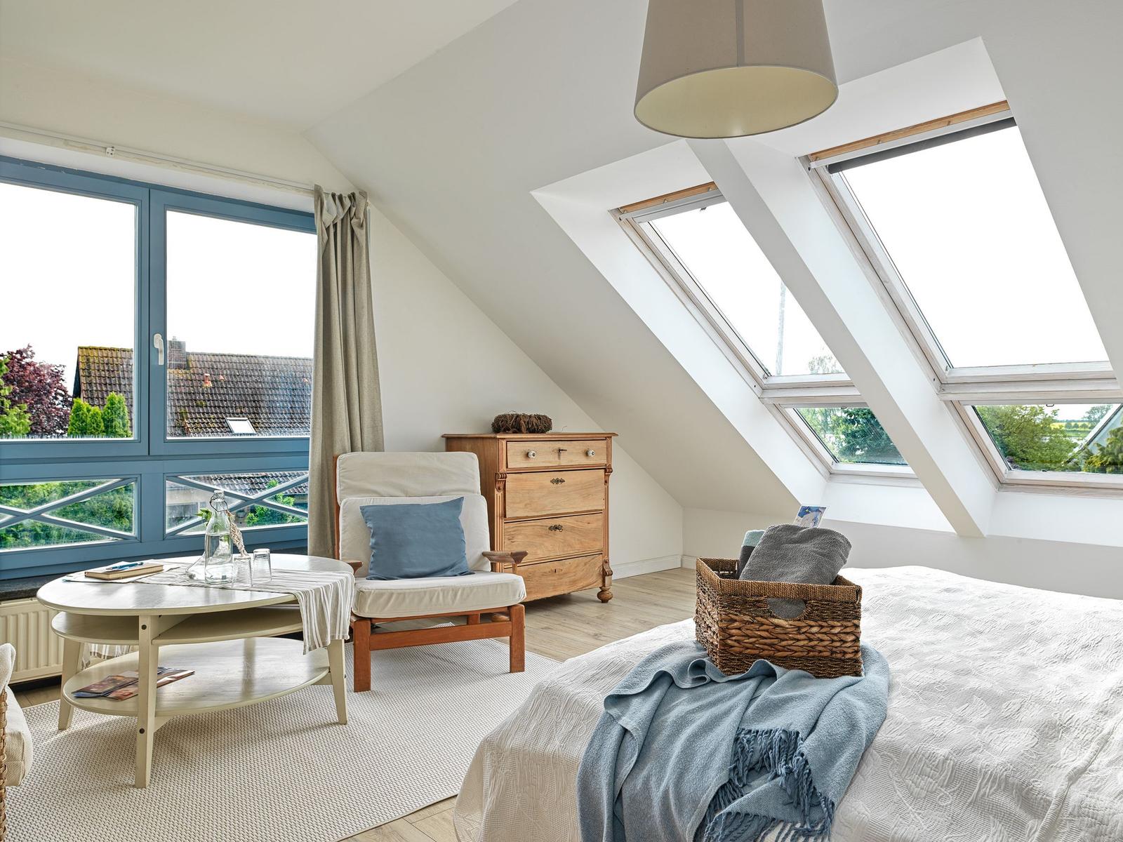 Schlafzimmer mit Dachschräge, Fenster und Bett.