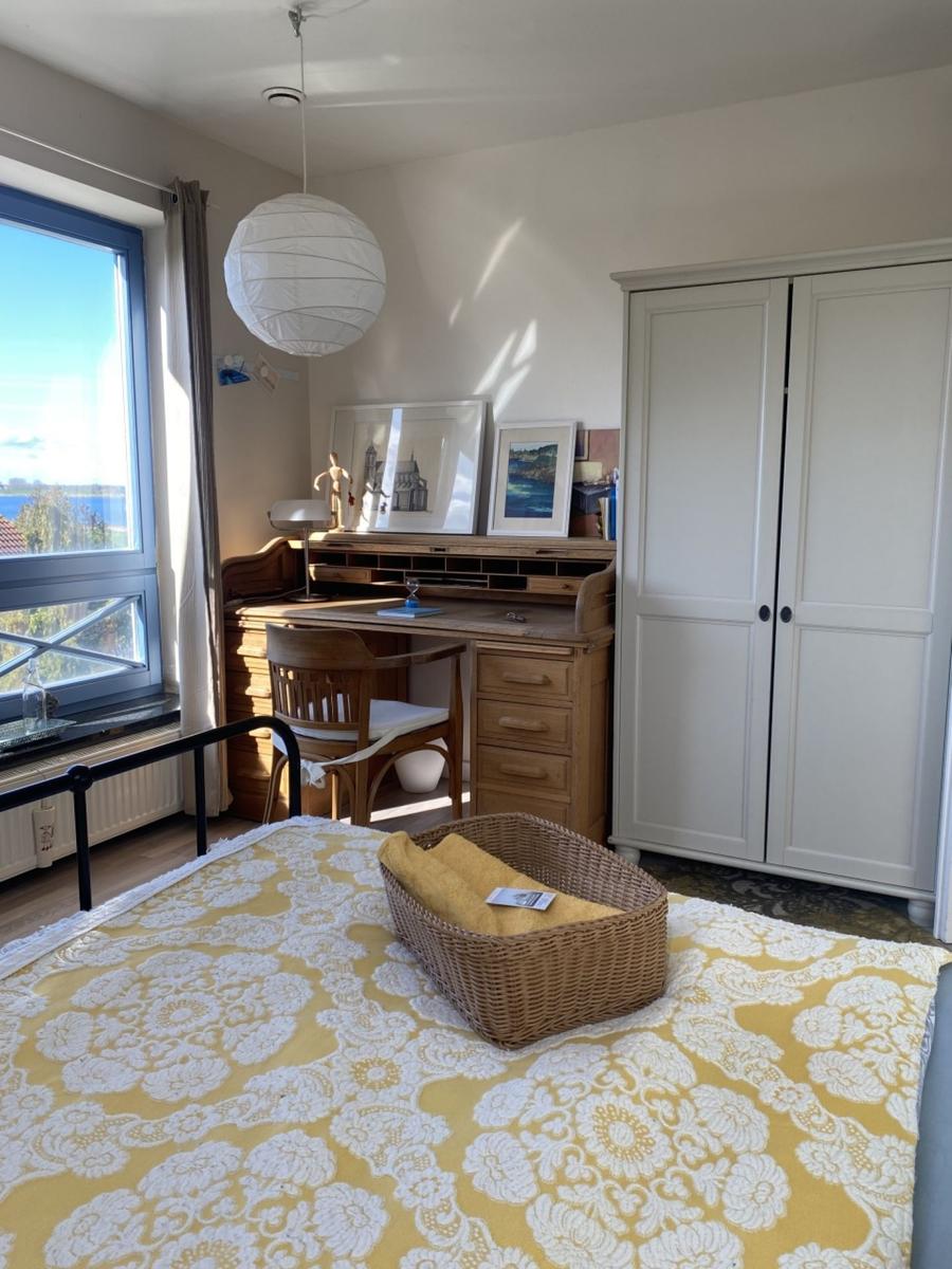 Schlafzimmer mit Schreibtisch, Kleiderschrank und Blick auf Wasser