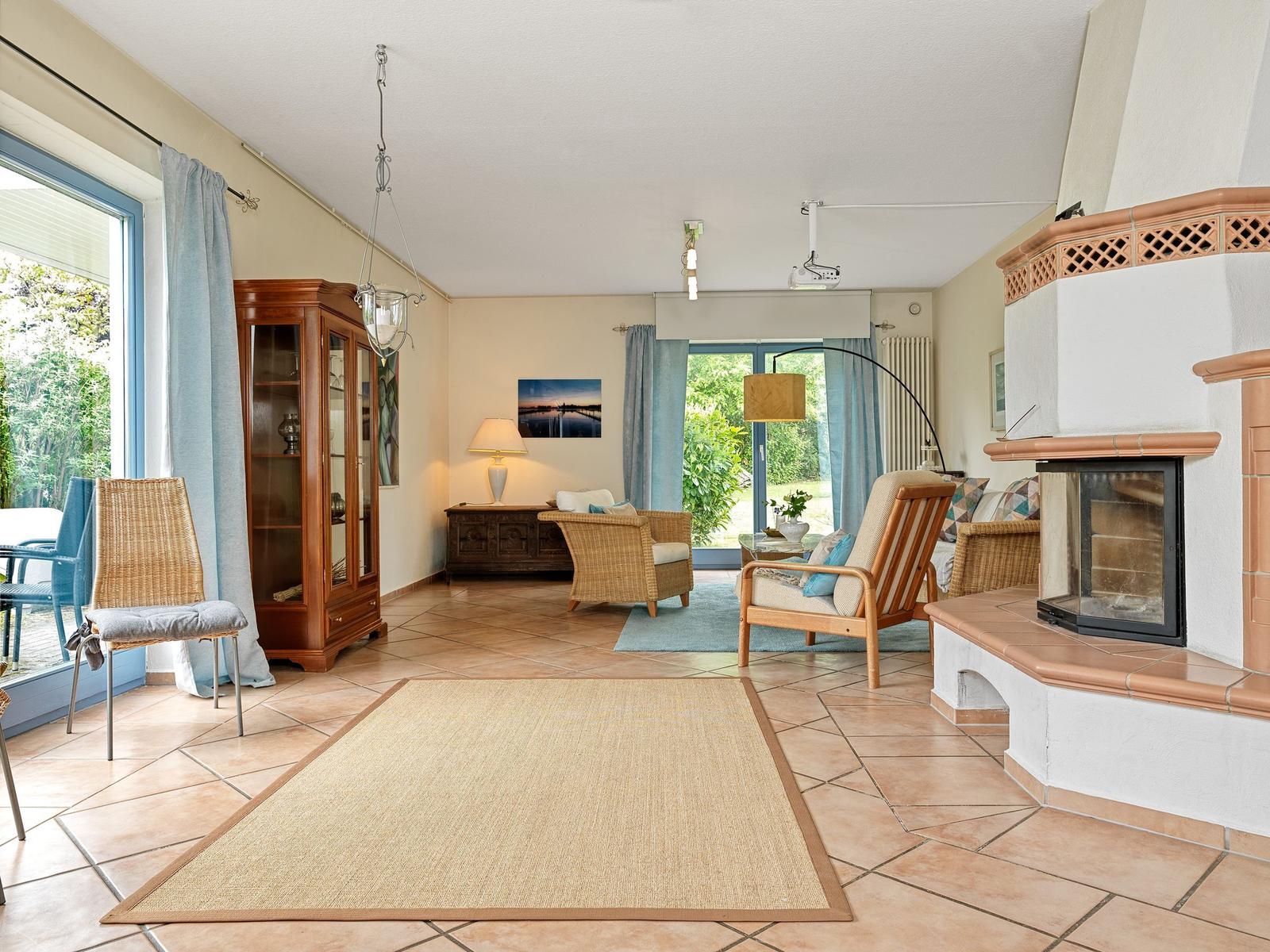 Wohnzimmer mit Kamin, Sitzgelegenheiten und Terrassentür.
