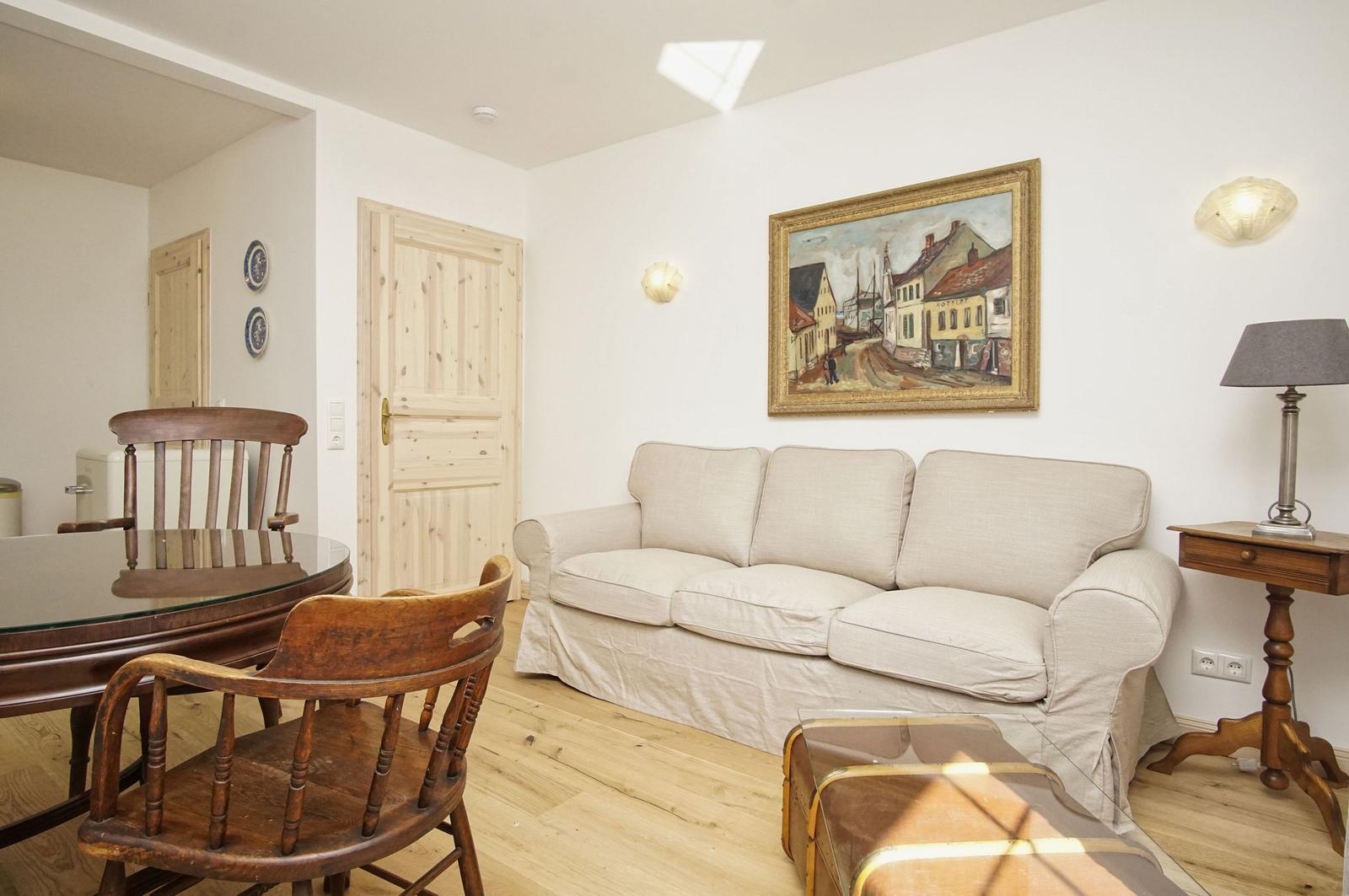 Wohn- und Essbereich mit Sofa, Holztisch, Stühlen und Wandbild.