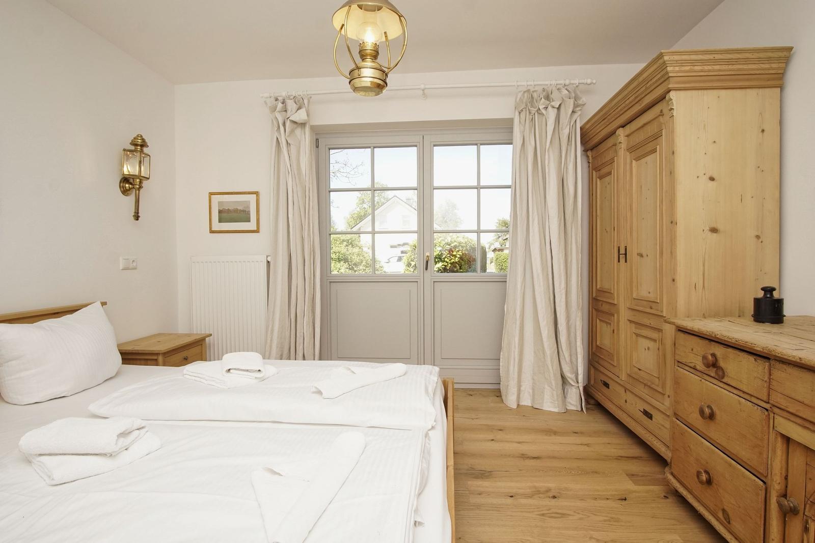 Schlafzimmer mit Holzbett, Kleiderschrank und Fenster zur Außenseite.