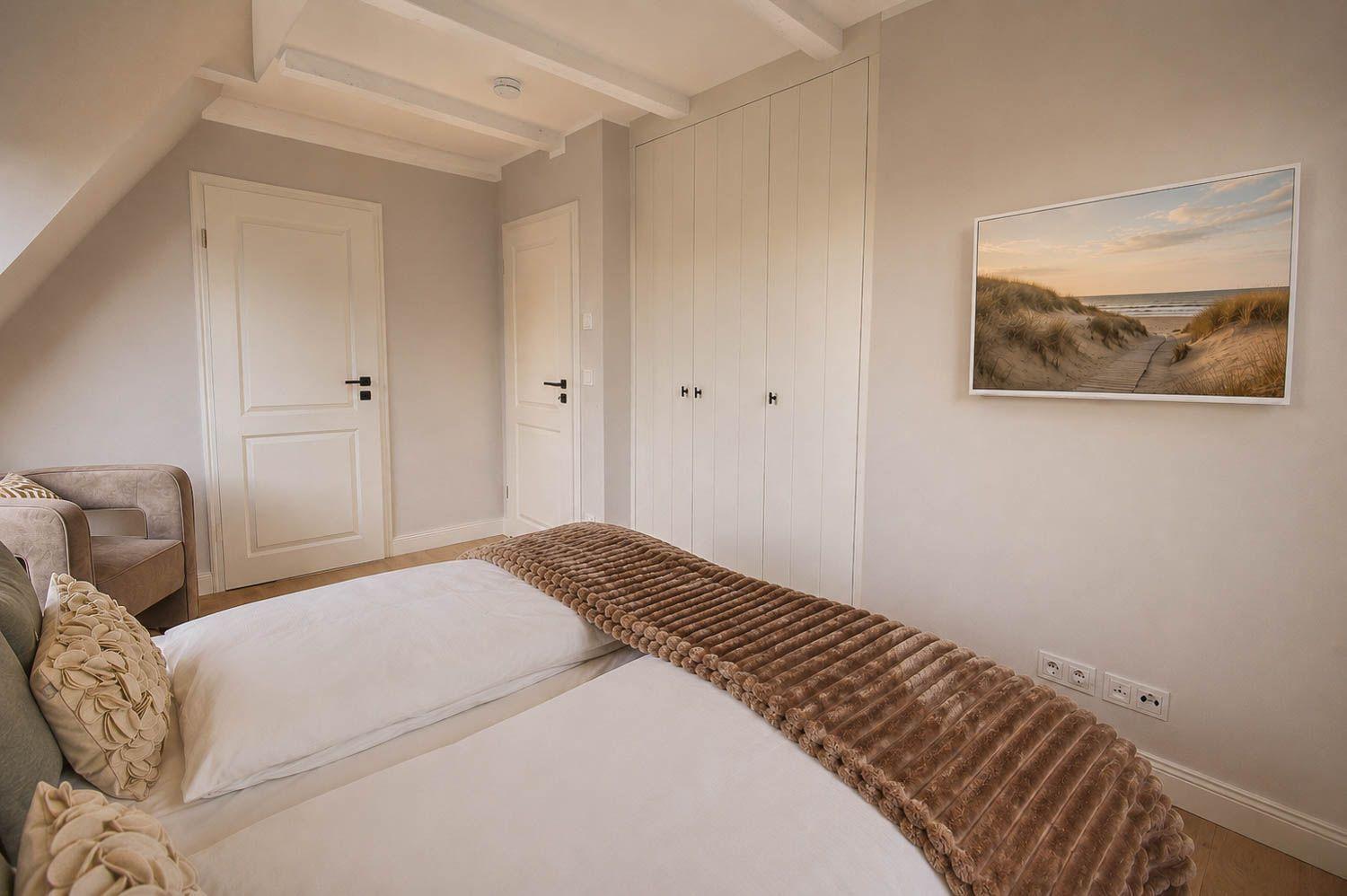 Schlafzimmer mit Bett, Kleiderschrank und Wandbild