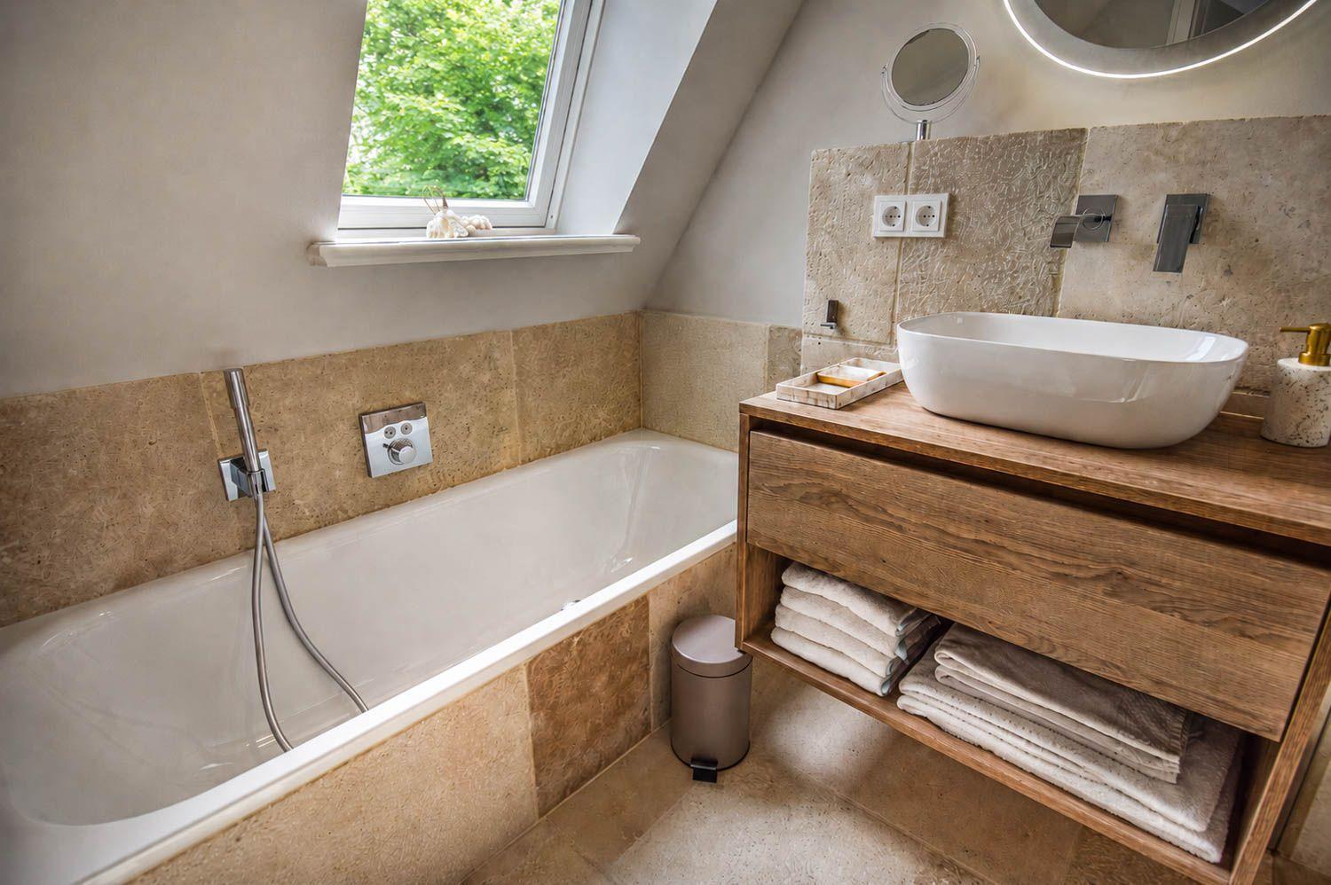 Bad mit Badewanne, Waschbecken und Dusche. Fenster mit Blick auf Bäume.