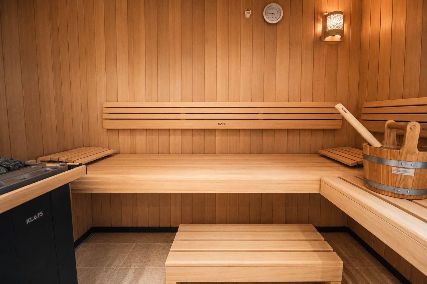 Sauna mit Holzbank, Thermometer und Holzwaschkarre.