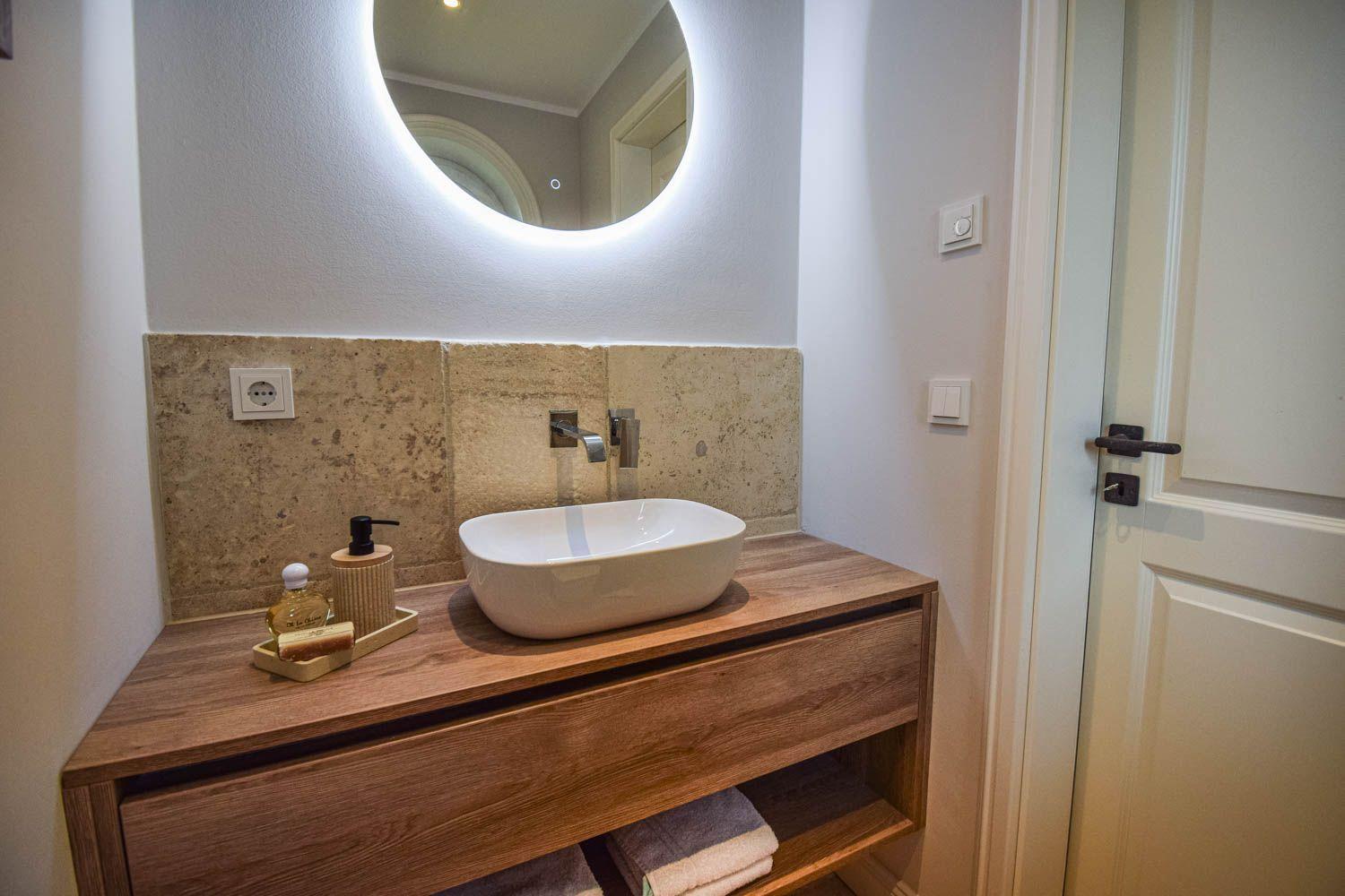 Badezimmer mit Waschtisch, Spiegel und Handtuchregal.