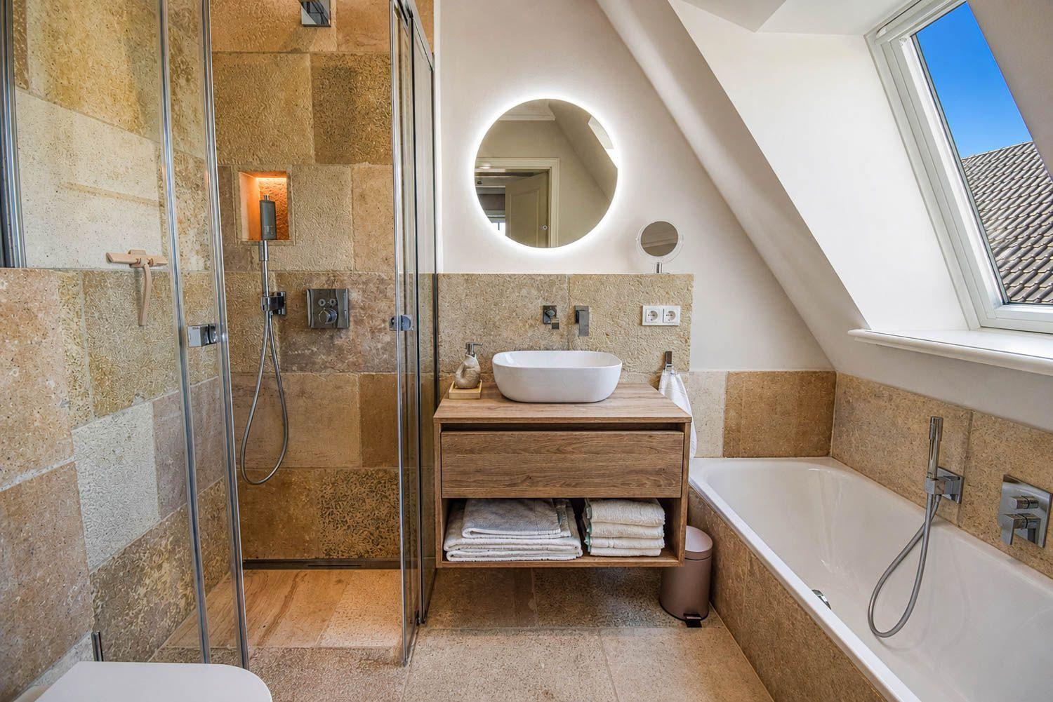 Badezimmer mit Dusche, Badewanne und Waschtisch unter Dachschrägen.