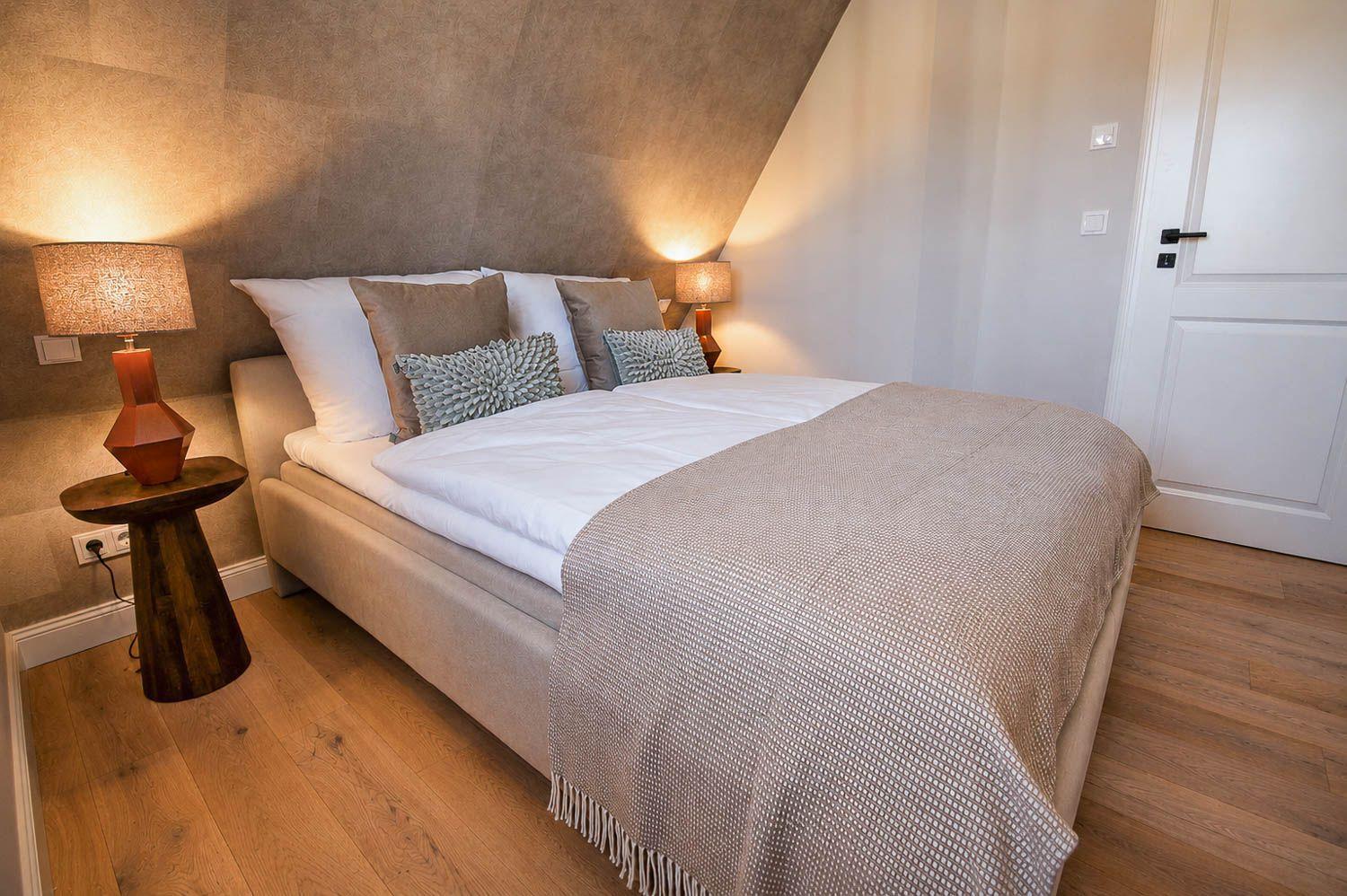 Schlafzimmer mit Doppelbett, Holzboden und zwei Nachttischen mit Lampen.