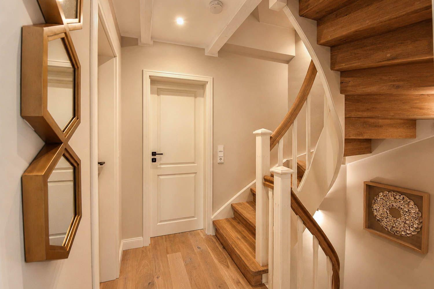 Hausflur mit Holztreppe, Spiegel und Wanddekoration.