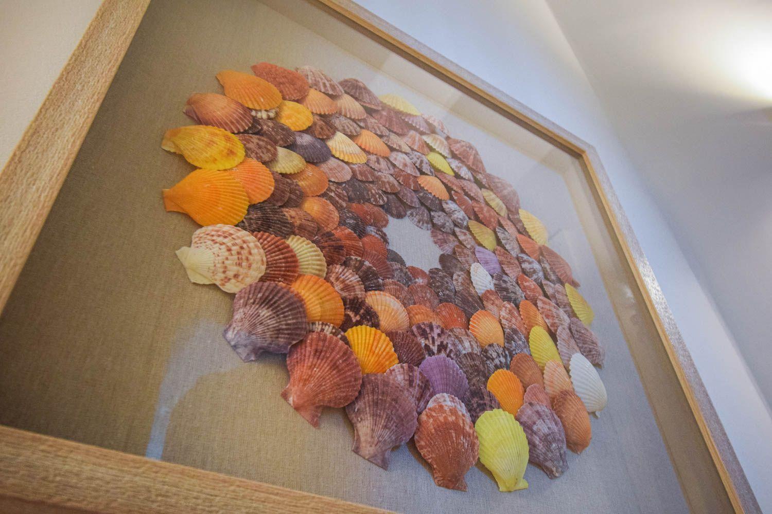 Framed artwork with colorful seashells arranged in a circular pattern.