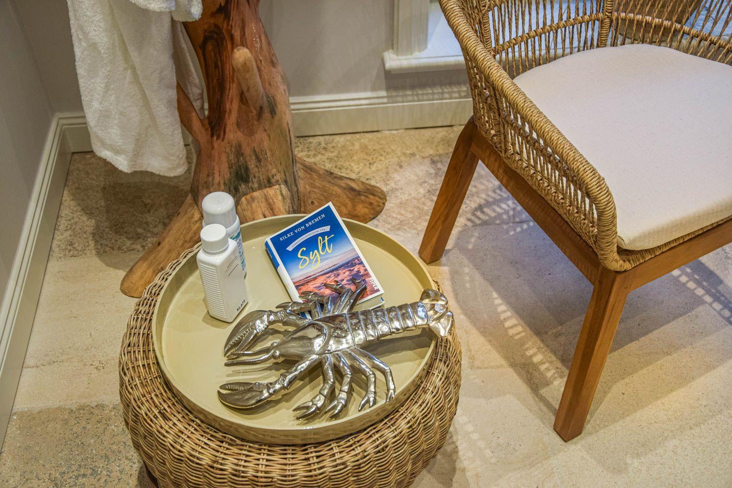 Rattan-Stuhl neben einem runden Tisch mit Buch und Metallkrebsschale.