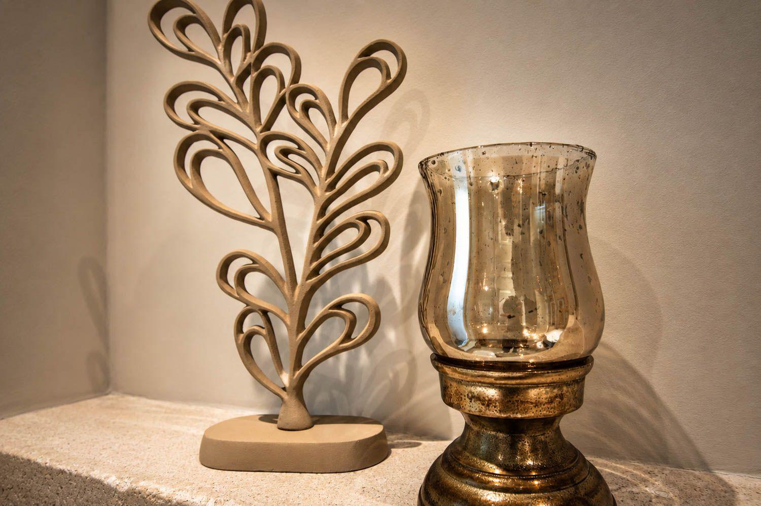 Eine dekorative Skulptur und eine goldfarbene Lampe auf einer Steinplatte.