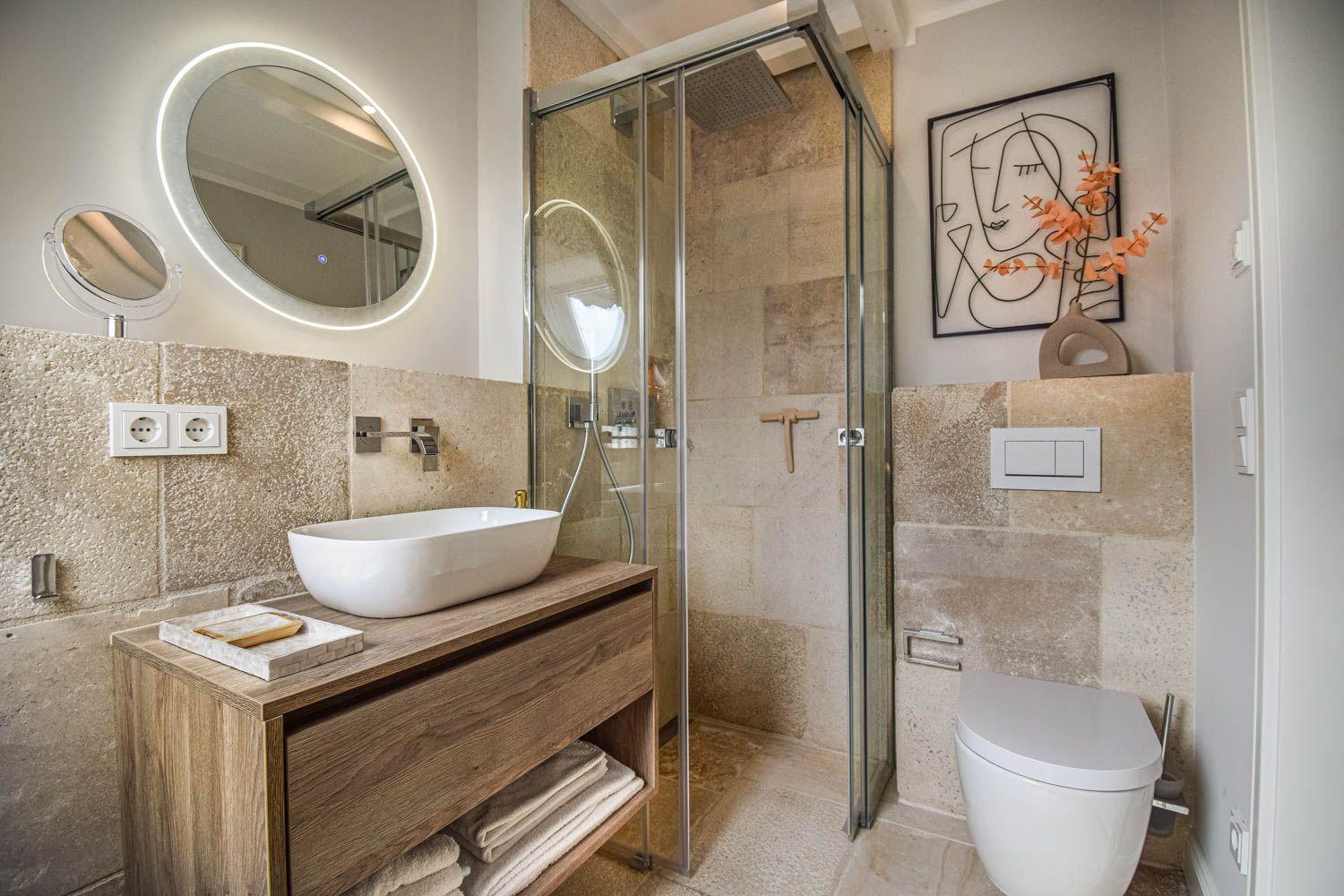 Bad mit Dusche, Waschbecken und Toilette. Steinwand und Holzschrank.