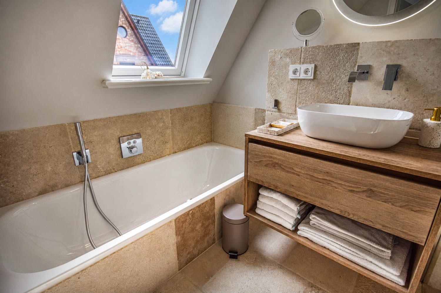 Badezimmer mit Badewanne, Waschbecken und Dusche unter Dachfenster.