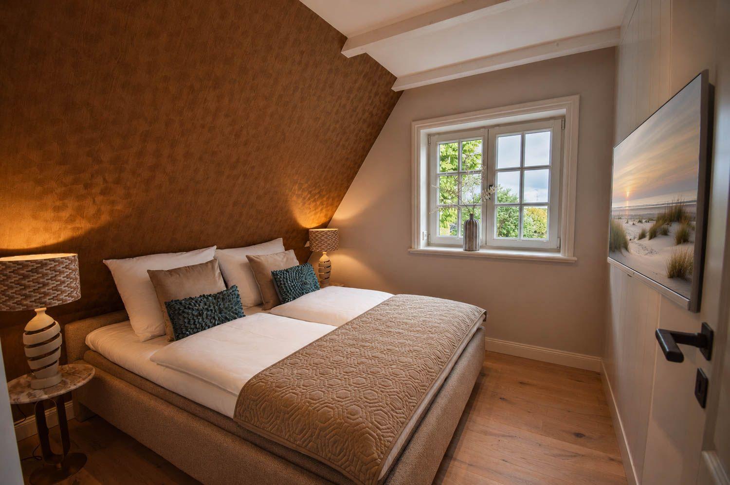 Schlafzimmer mit Dachschrägen, Bett, Fenster und Wandbild.