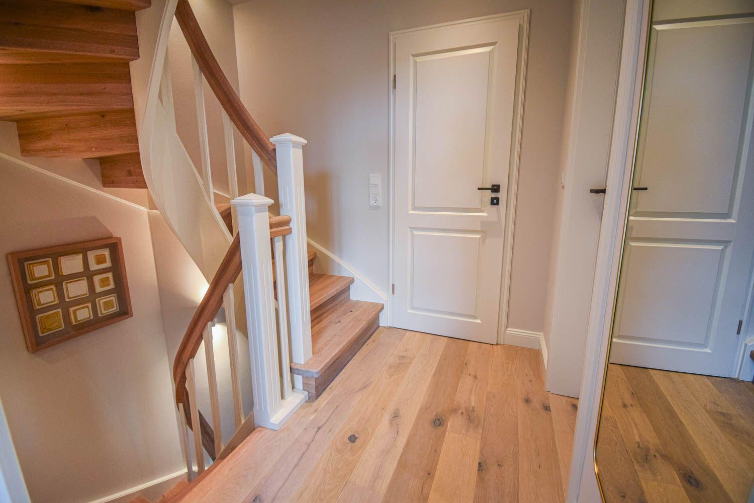 Haus mit Holztreppe, weißen Türen und Holzboden im Flur.