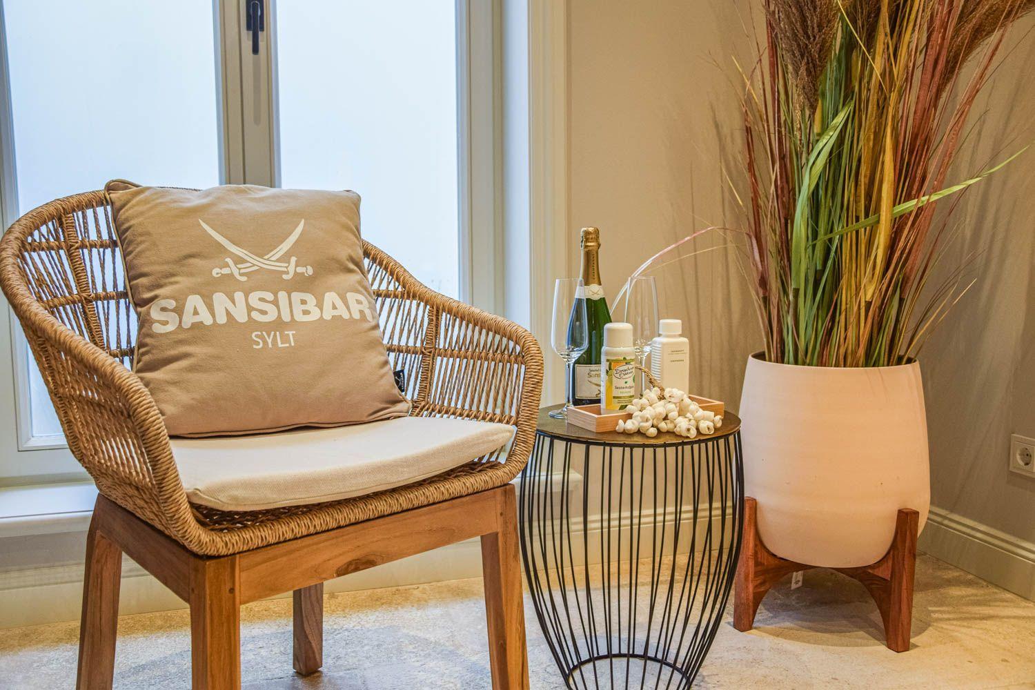 Rattan-Stuhl mit Kissen, kleiner Tisch und Pflanze in einem Raum.